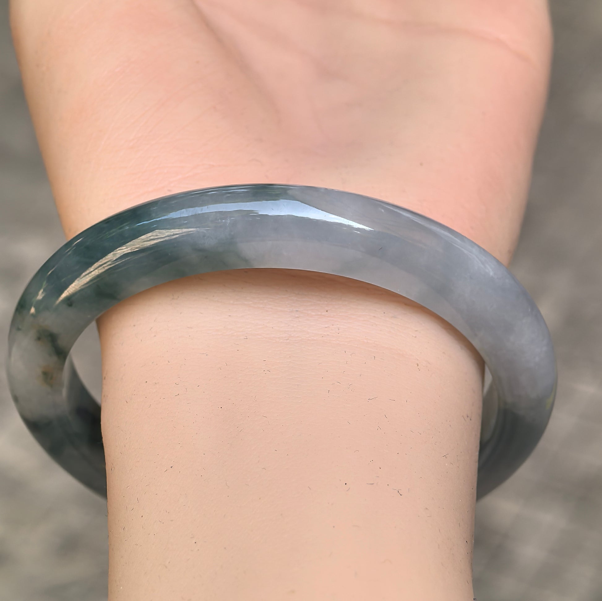 Close-up of icy glutinous jadeite bangle showing cool green tone and glossy surface.
