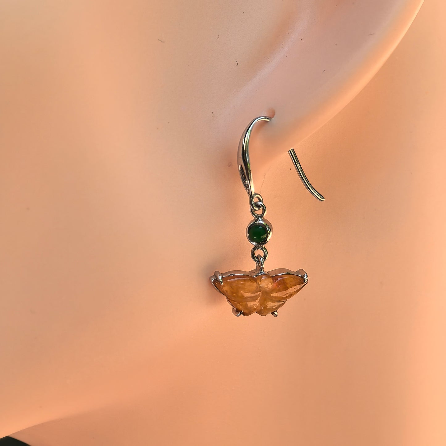 Natural Grade-A icy honey yellow butterfly jadeite earring worn on a display ear.
