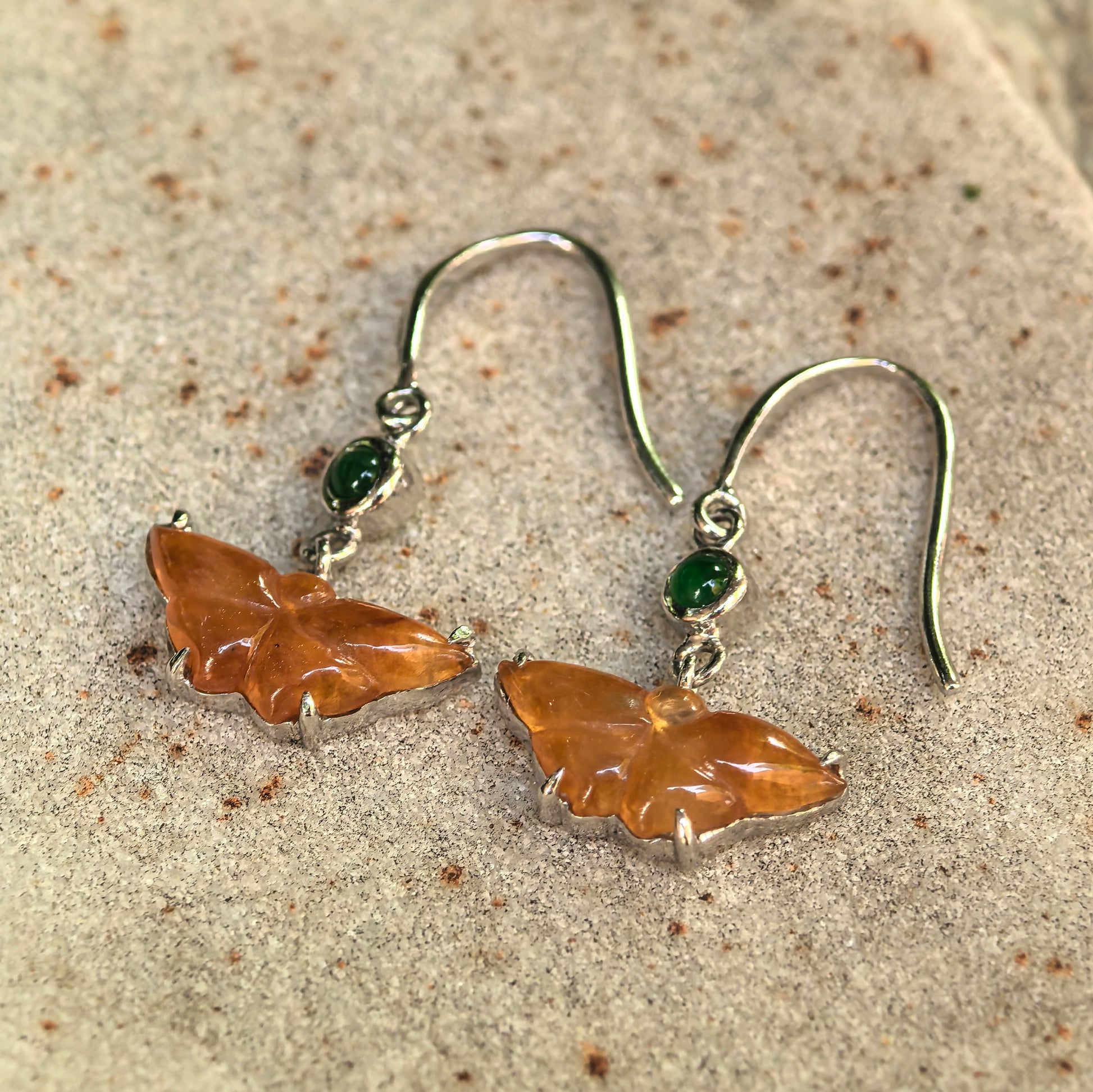 Close-up of icy honey yellow butterfly jadeite earrings with 18K gold hook setting.
