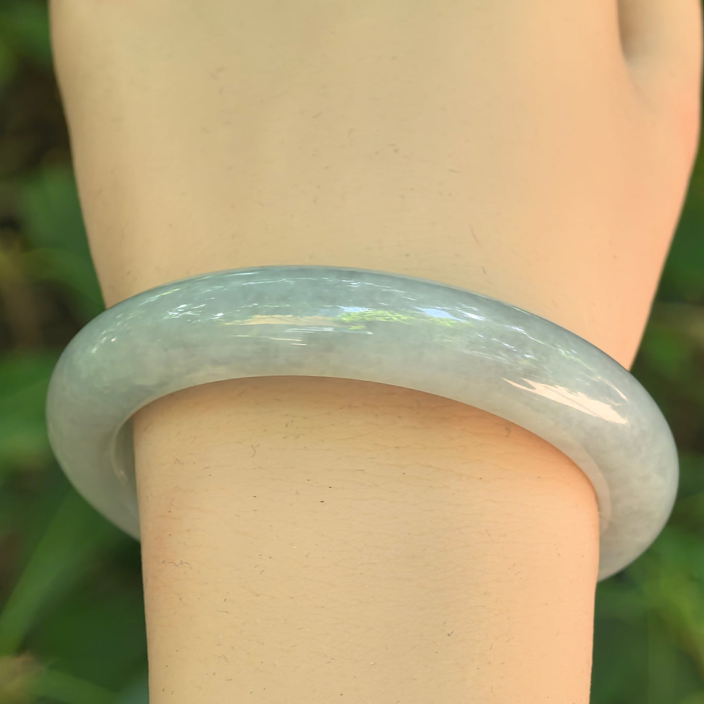 Close-up of pale green jadeite bangle showing smooth polish and soft glutinous translucency.

