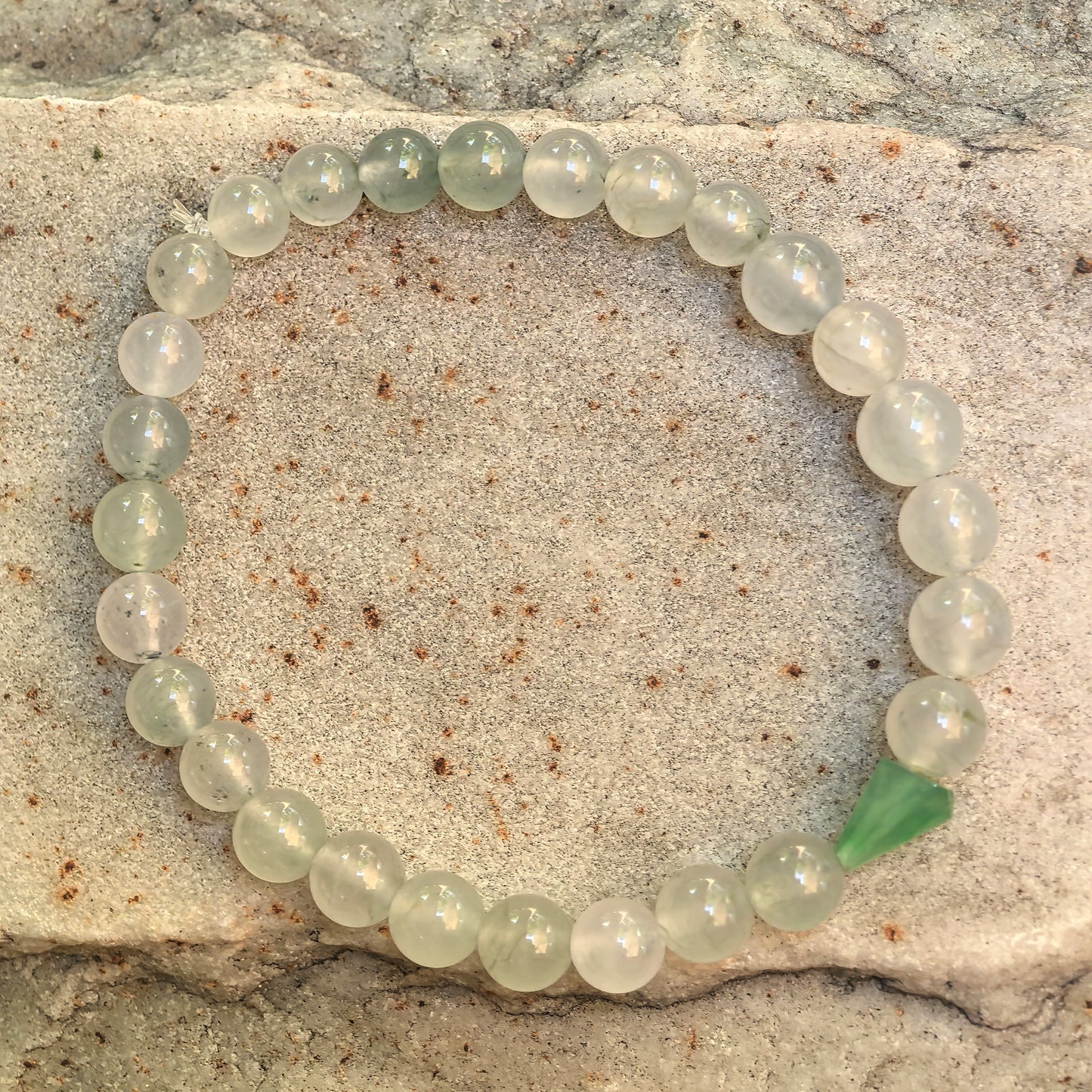 Close-up of icy translucent jadeite beads with green freeform accent piece.
