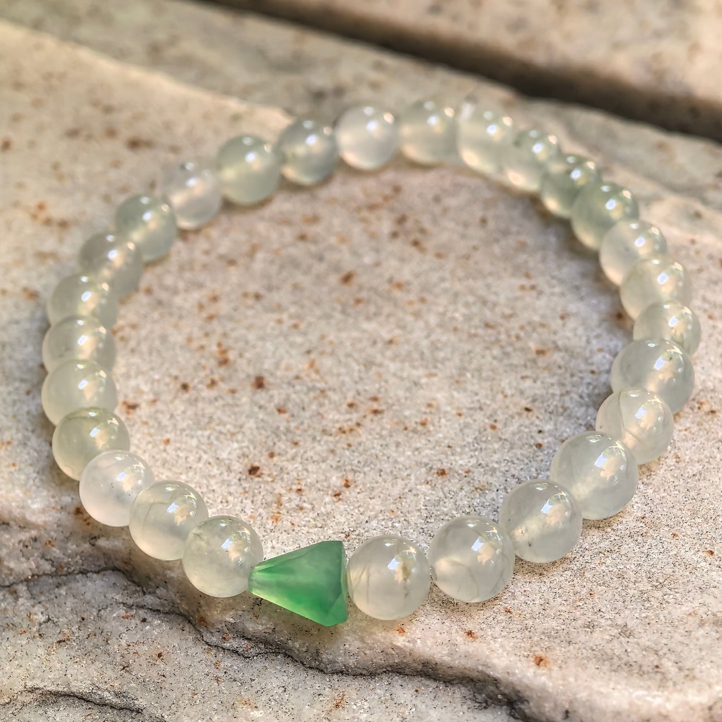 White and pale green jadeite bead bracelet showing natural internal lines and soft luster.
