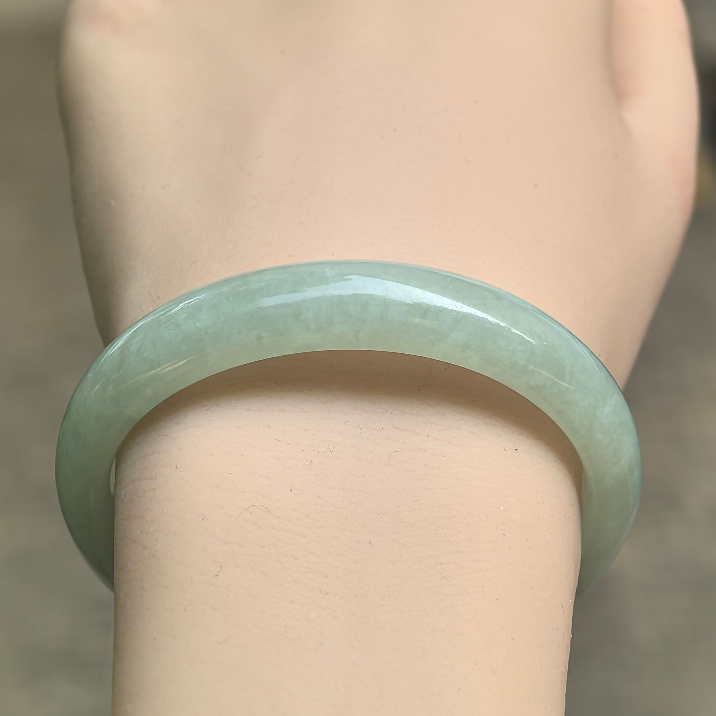 Close-up of icy glutinous mint green jadeite bangle showing gentle translucency and rounded polish.
