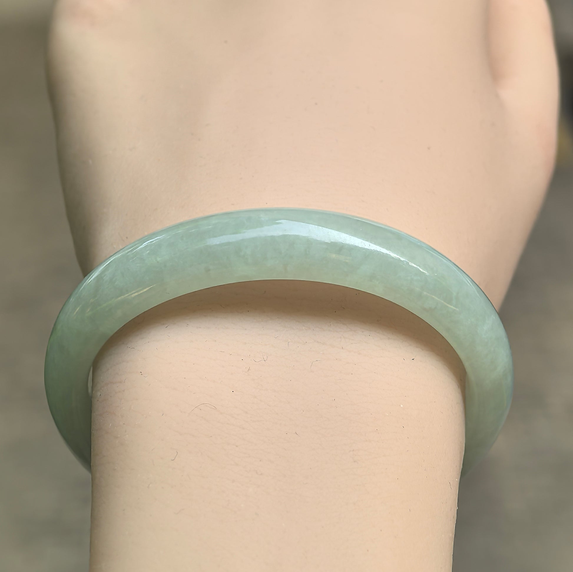 Close-up of icy glutinous mint green jadeite bangle showing gentle translucency and rounded polish.
