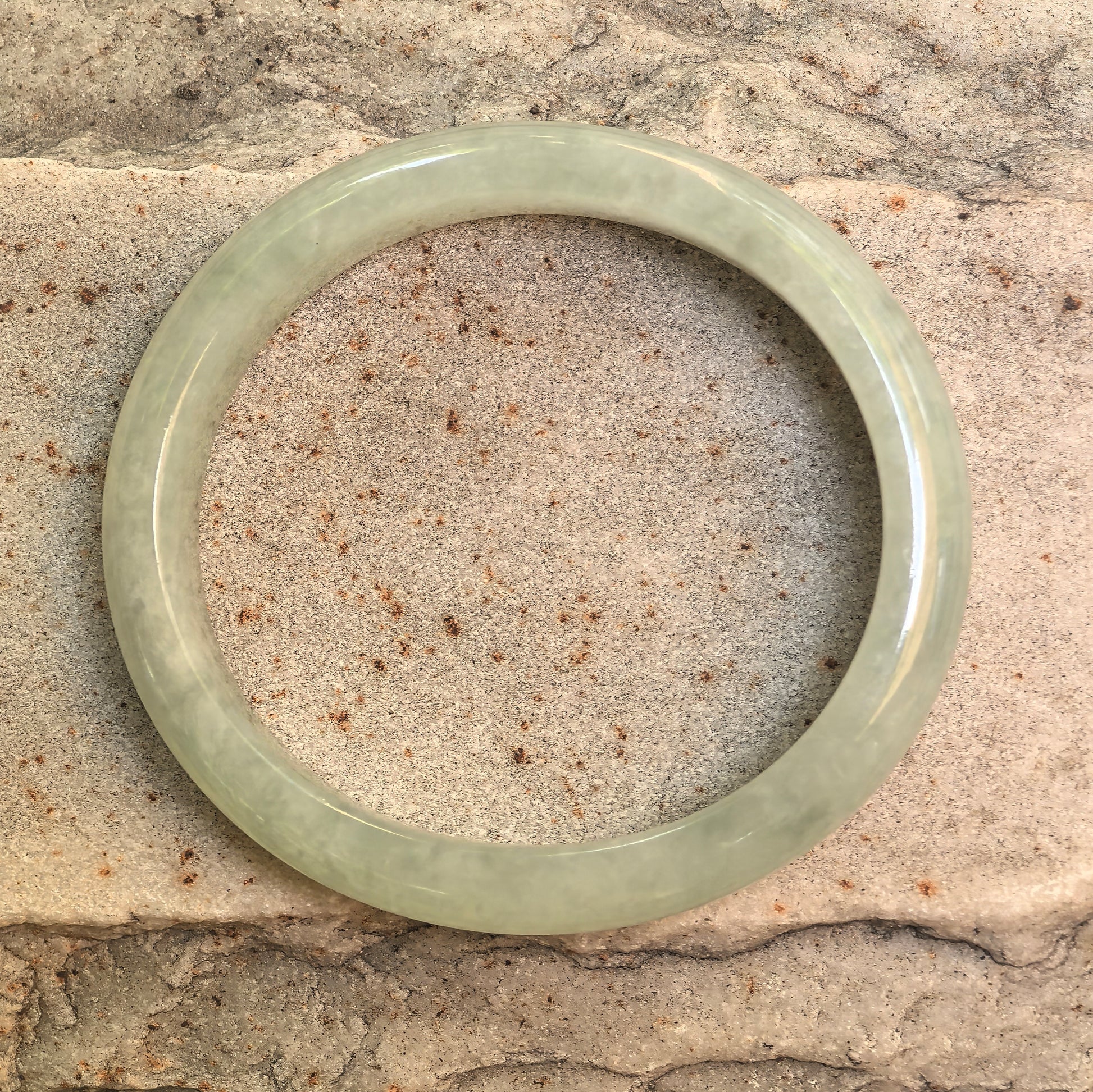 Front view of pale mint green oval jadeite bangle showing its princess-style inner shape.
