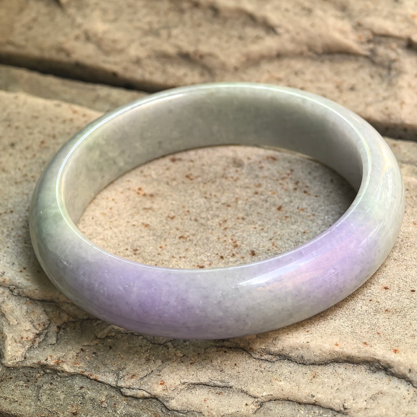 Side view of NGTC certified bean glutinous jadeite bangle, showing wide D-shape body, soft translucency, and polished finish.

