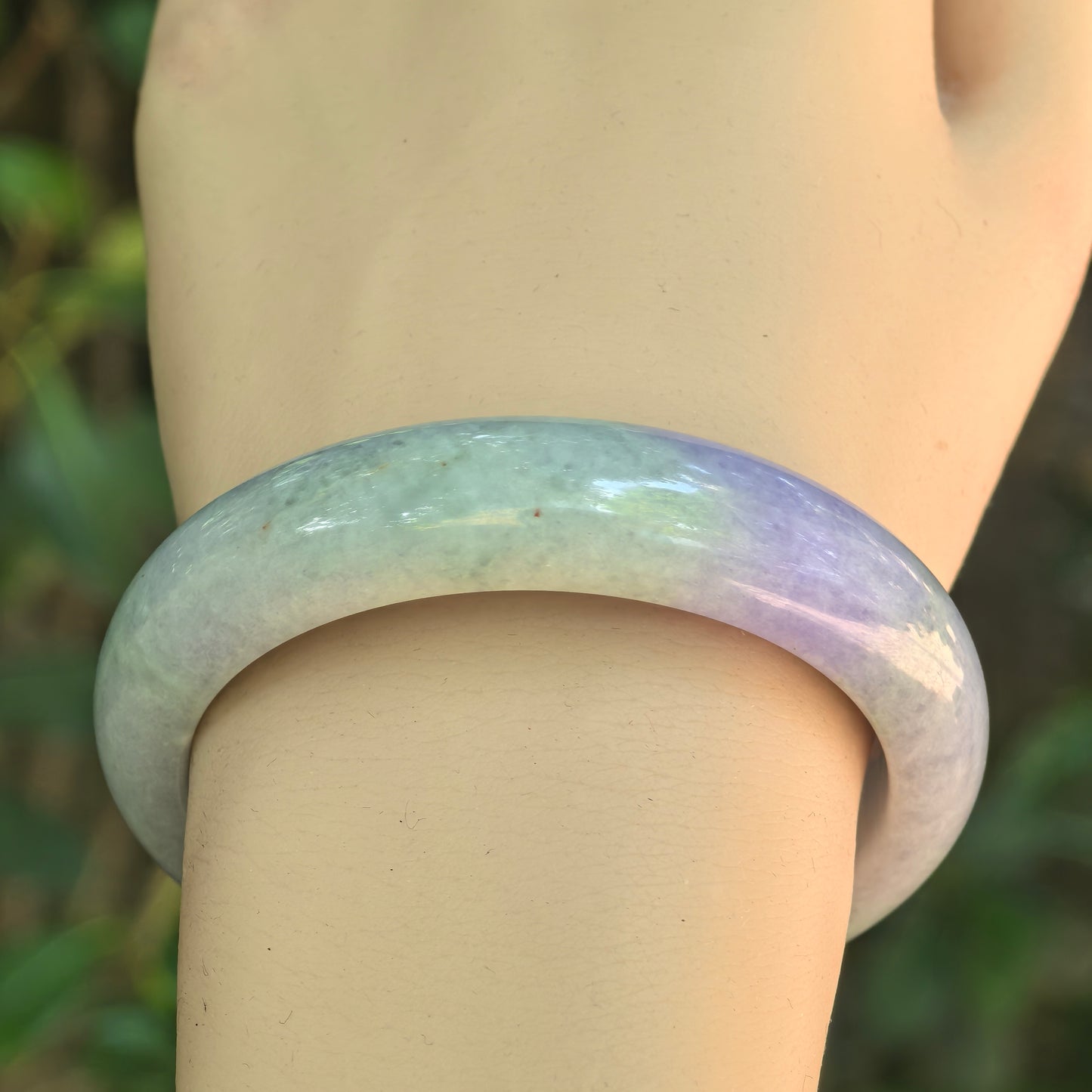 Close-up of bean glutinous jadeite bangle on wrist, showing lavender-purple section, light green base, and natural texture.