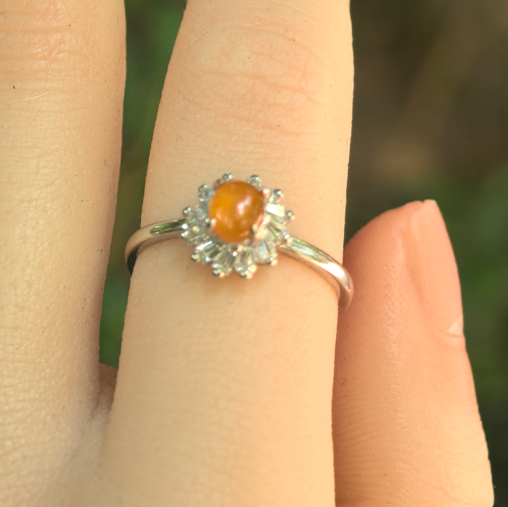 Close-up of yellow oval cabochon jadeite ring with clear accent stones.