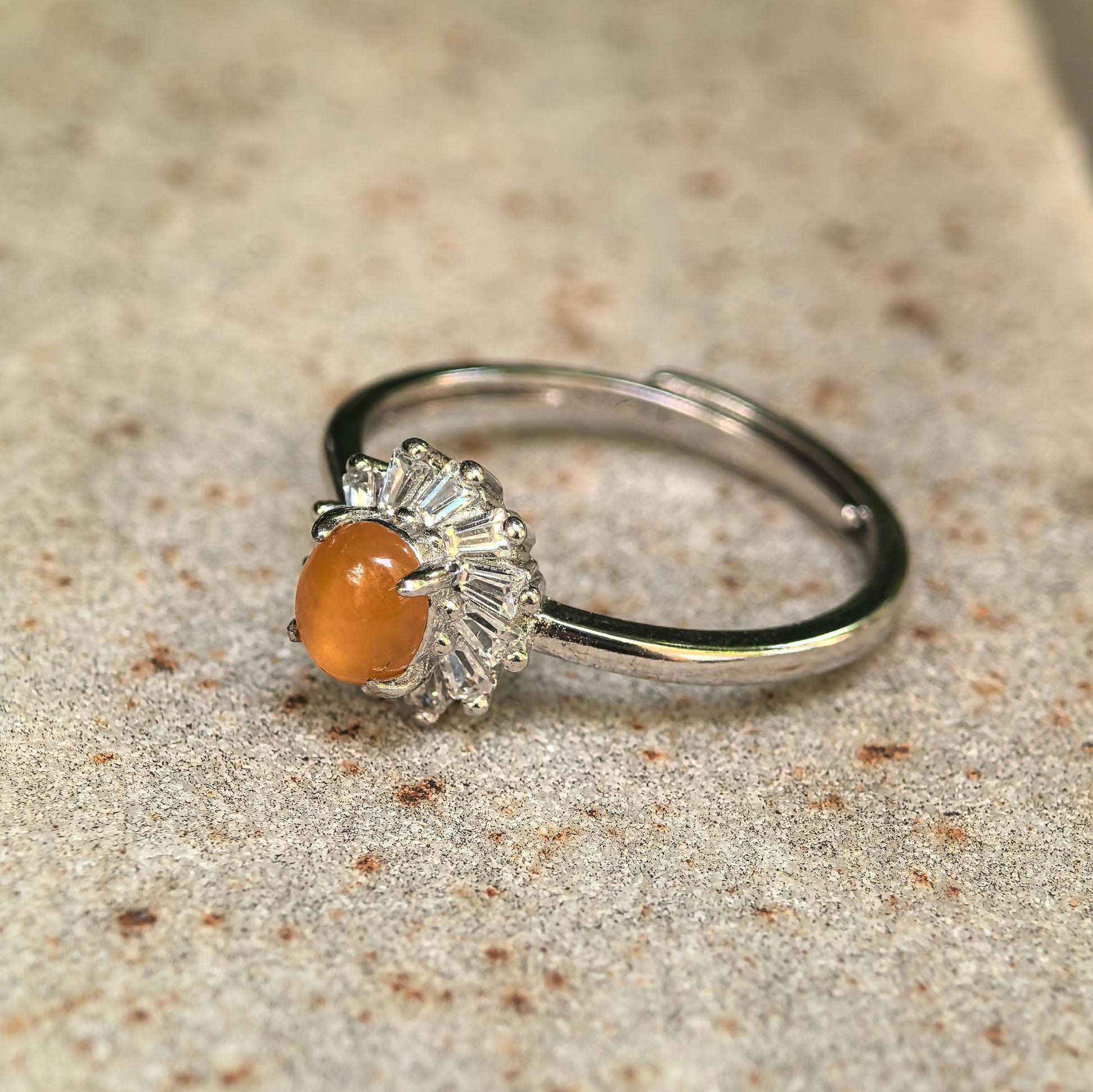 Natural yellow jadeite cabochon ring displayed on stone background.