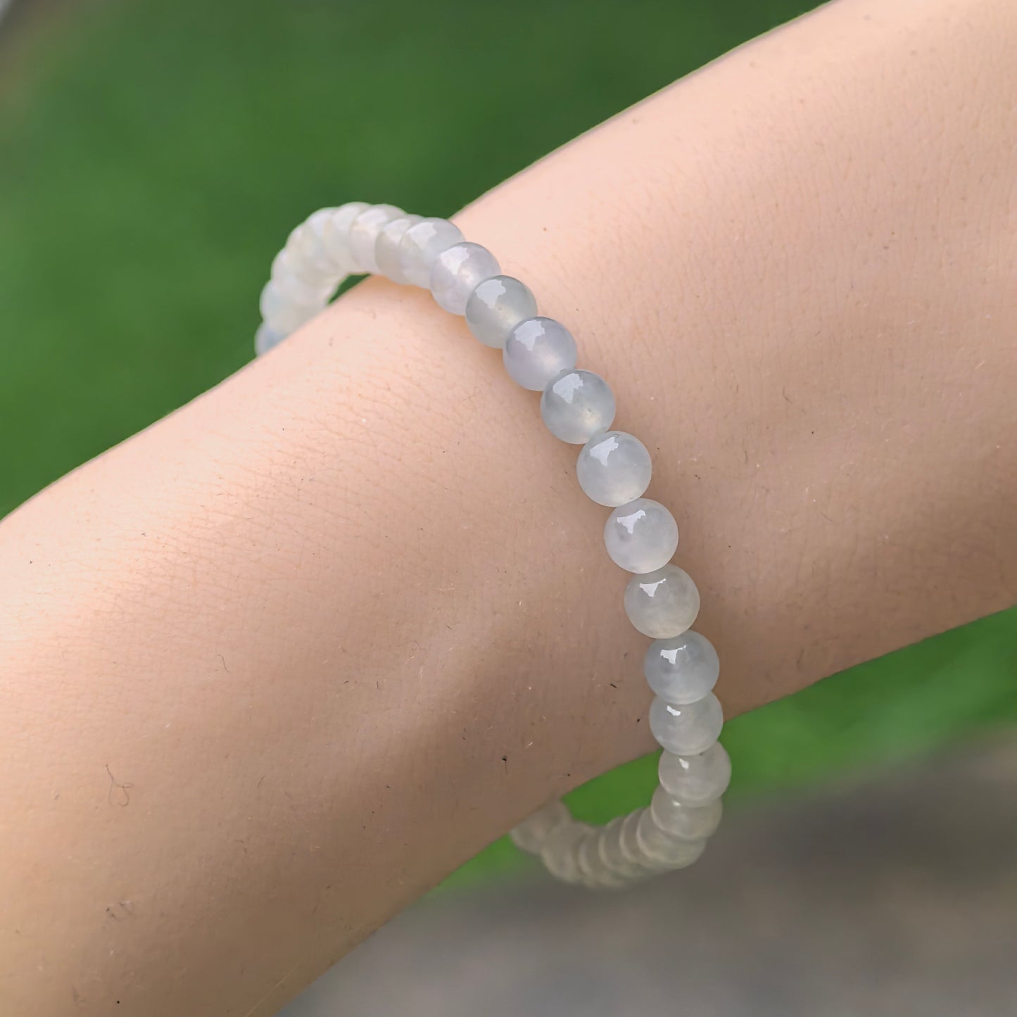 Natural Grade-A jadeite bracelet worn on wrist, showing delicate 4.9 mm icy white-green beads.
