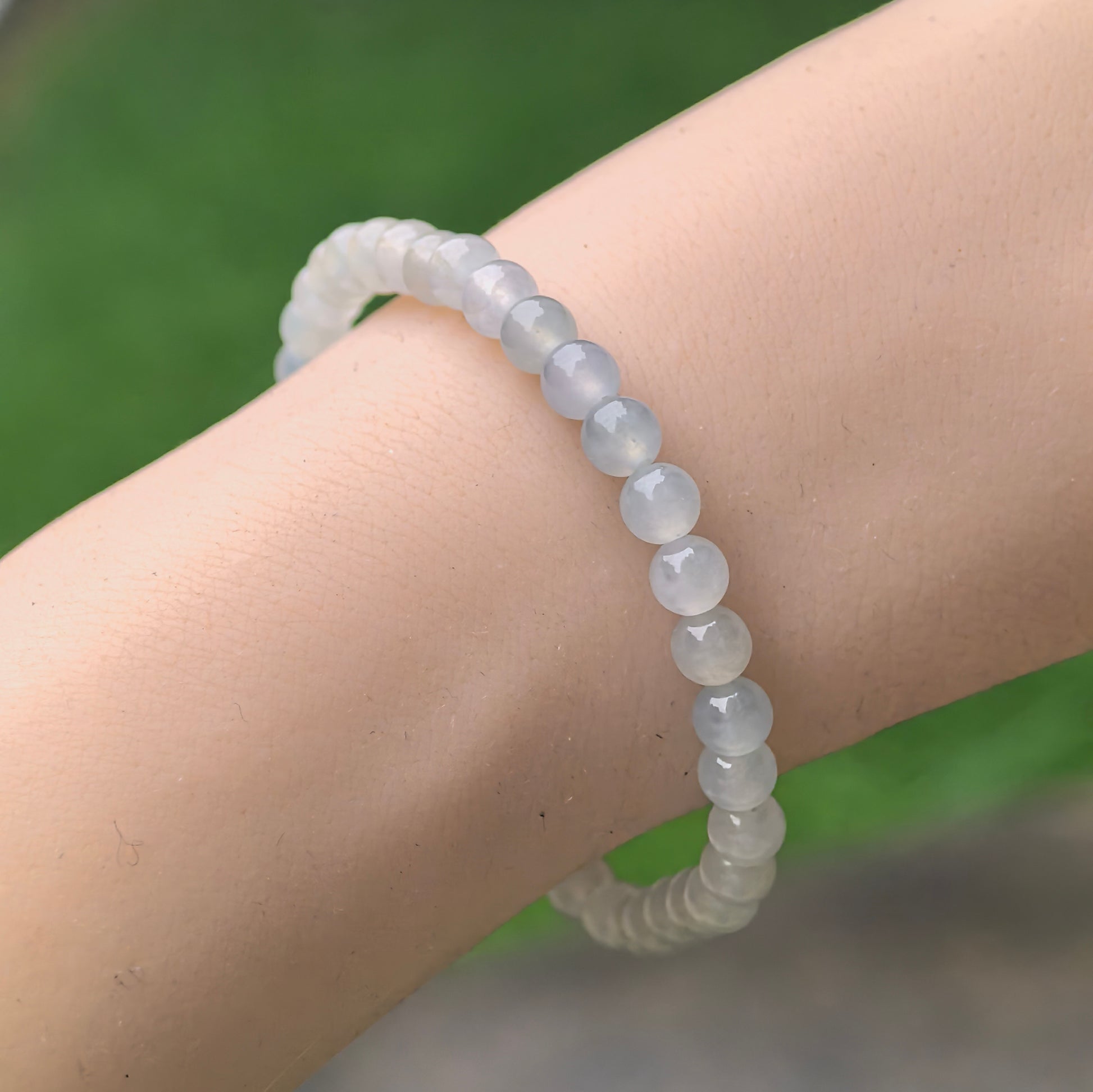 Natural Grade-A jadeite bracelet worn on wrist, showing delicate 4.9 mm icy white-green beads.
