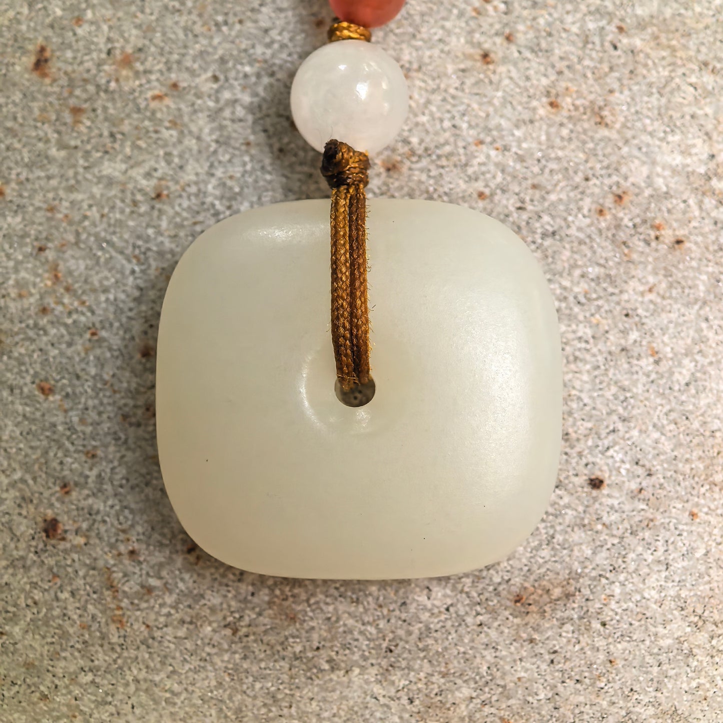 Close-up of natural white Hetian jade Peace Pendant on stone background with clean polished surface.
