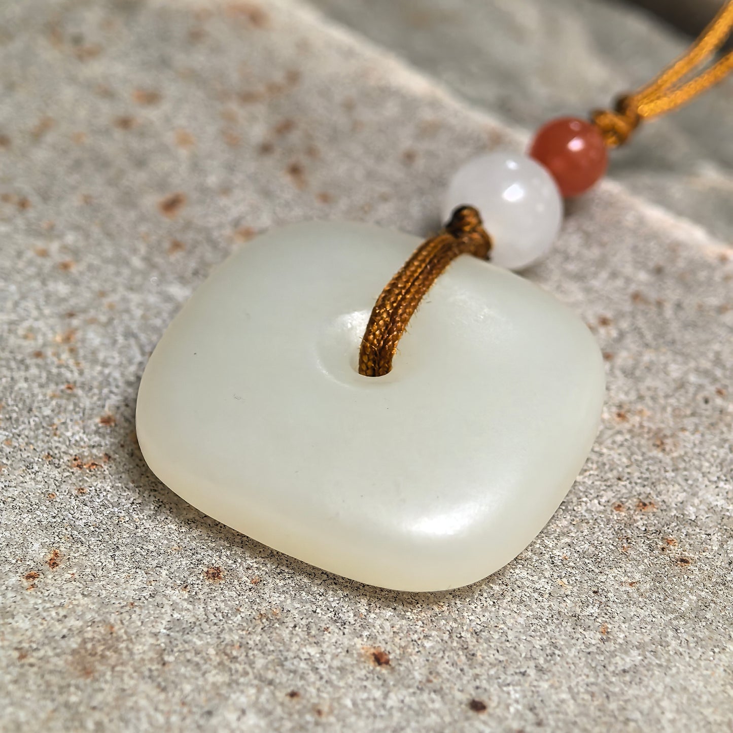 Detailed view of white Hetian jade square Peace Pendant showing the cord passing through the center opening.
