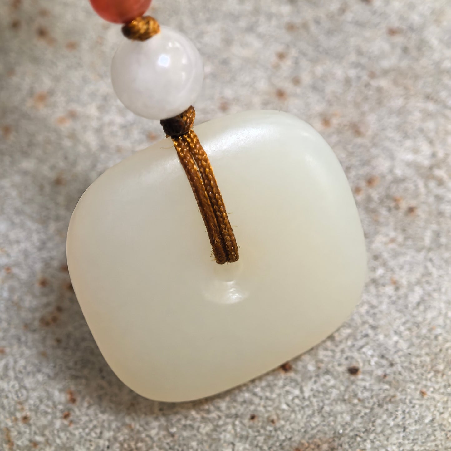 Close-up of natural white Hetian jade pendant showing fine texture and soft creamy white luster.
