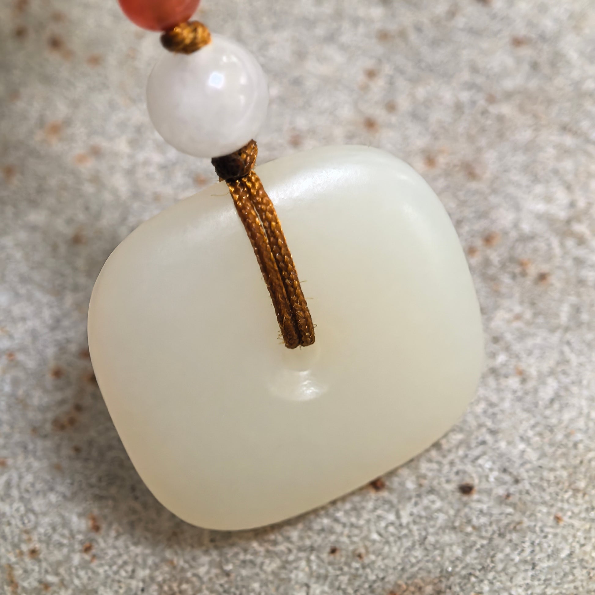 Close-up of natural white Hetian jade pendant showing fine texture and soft creamy white luster.

