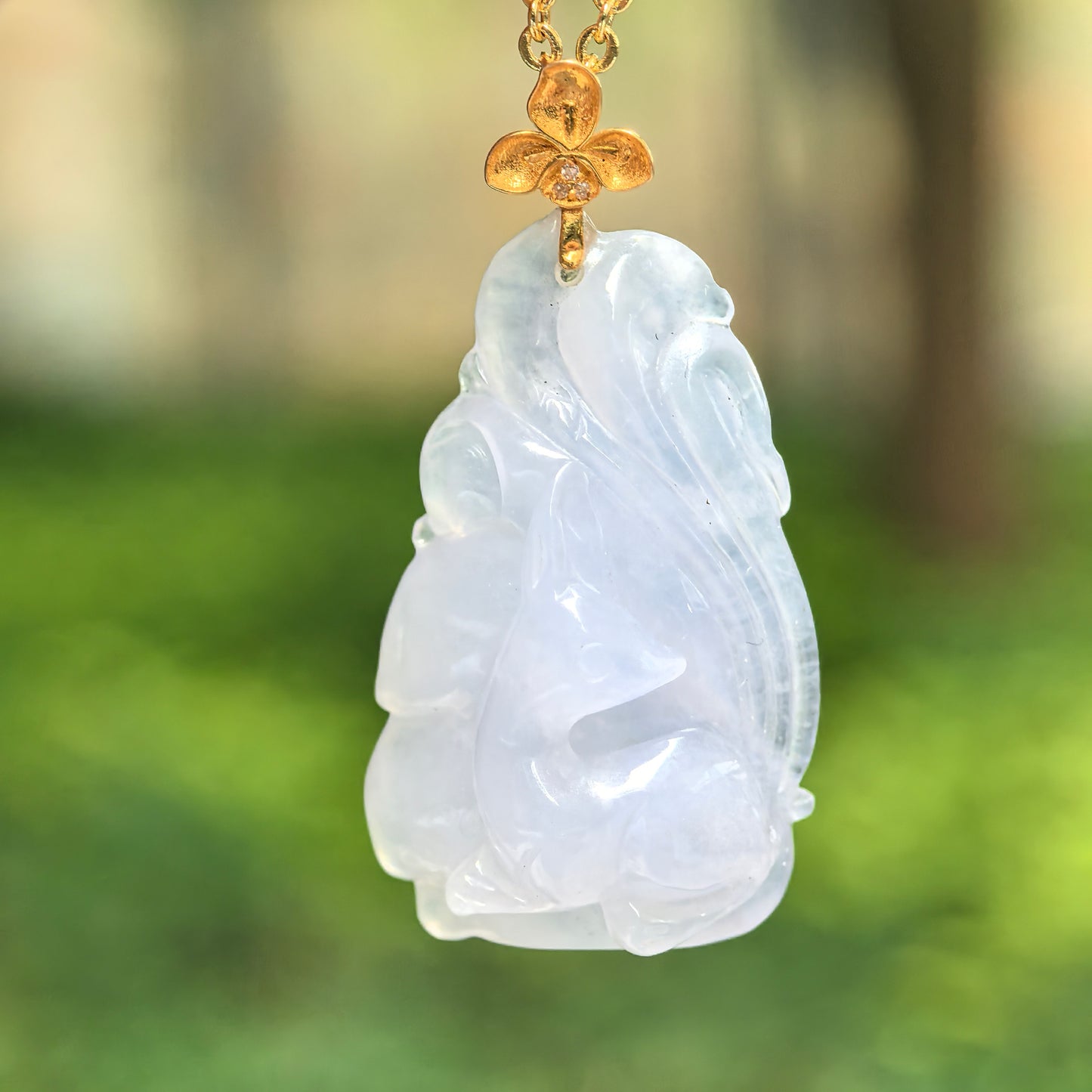 Natural Grade-A lavender jadeite fox pendant hanging outdoors with 18K gold flower bail.
