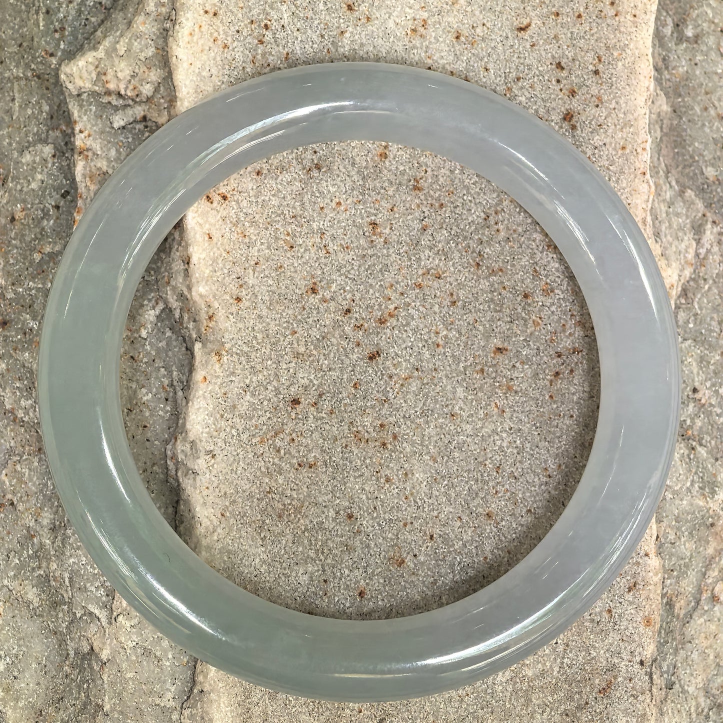 Top view of pale green round jadeite bangle showing circular shape and muted green-gray tone.
