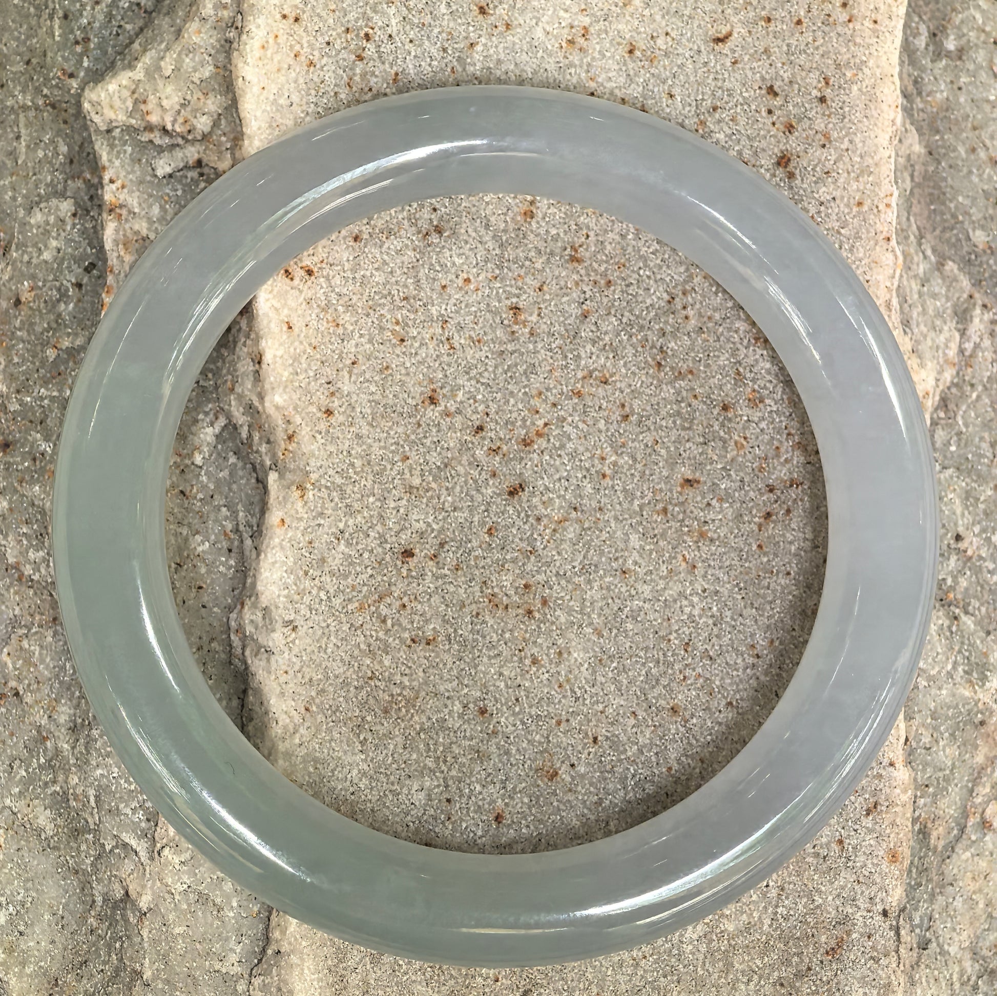 Top view of pale green round jadeite bangle showing circular shape and muted green-gray tone.