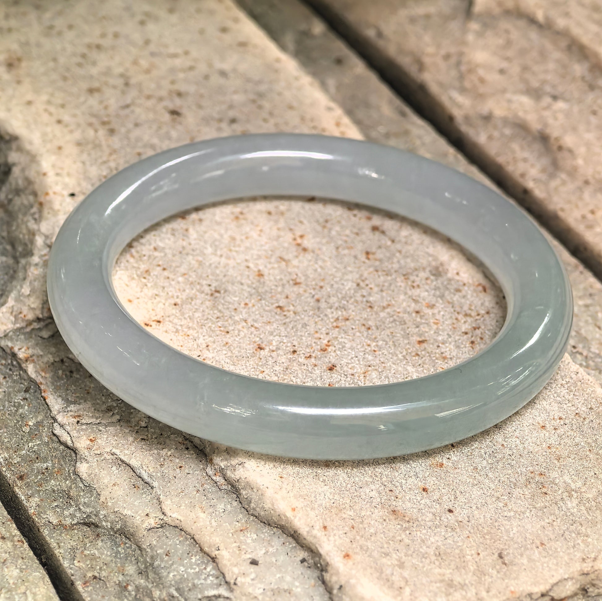 Side view of natural jadeite round bangle showing 9.4 mm width and smooth rounded profile.