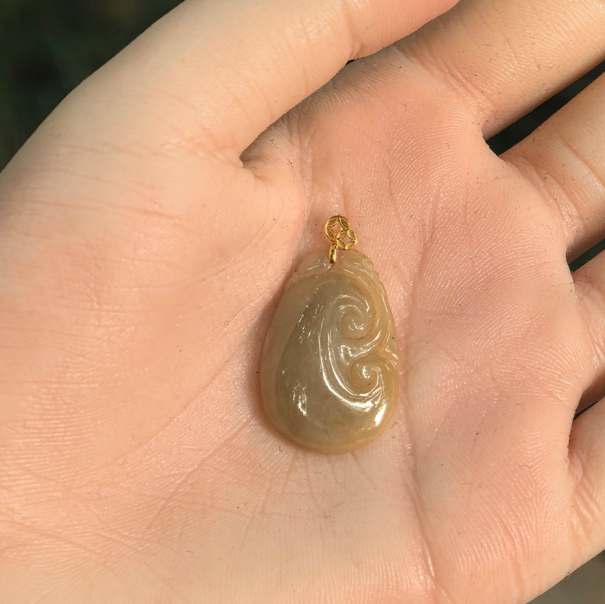 Petite Natural Grade-A yellow Ruyi jadeite pendant shown in hand for scale.