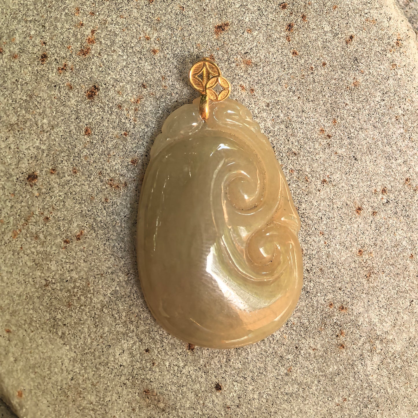 Side view of yellow Ruyi jadeite pendant showing warm tone, smooth polish, and gold bail.