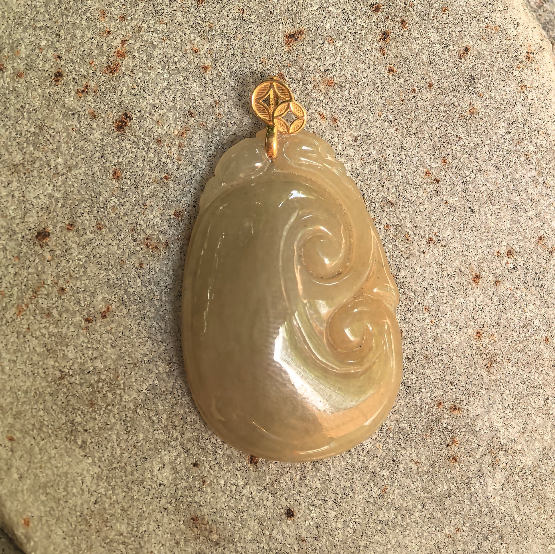 Side view of yellow Ruyi jadeite pendant showing warm tone, smooth polish, and gold bail.