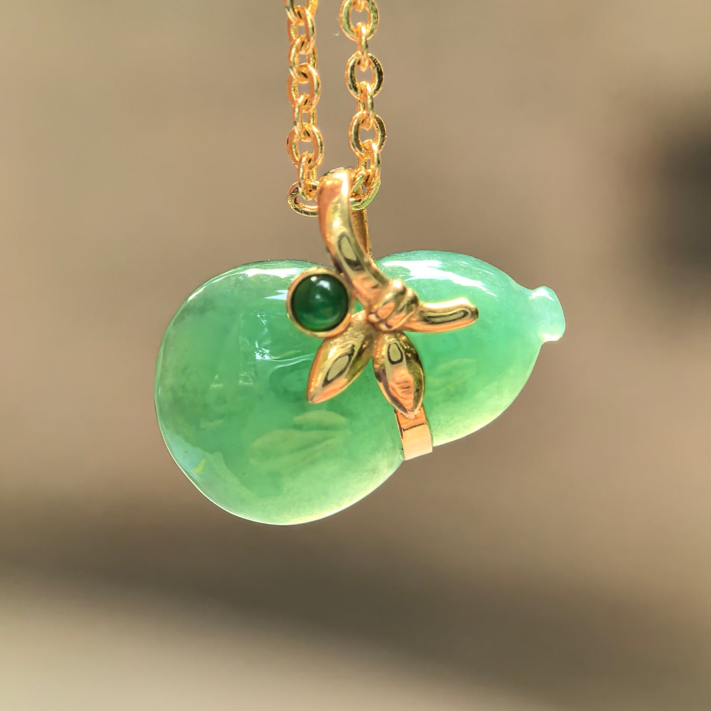 Natural Grade-A glutinous light green gourd jadeite pendant with 18K gold setting hanging on a gold chain.