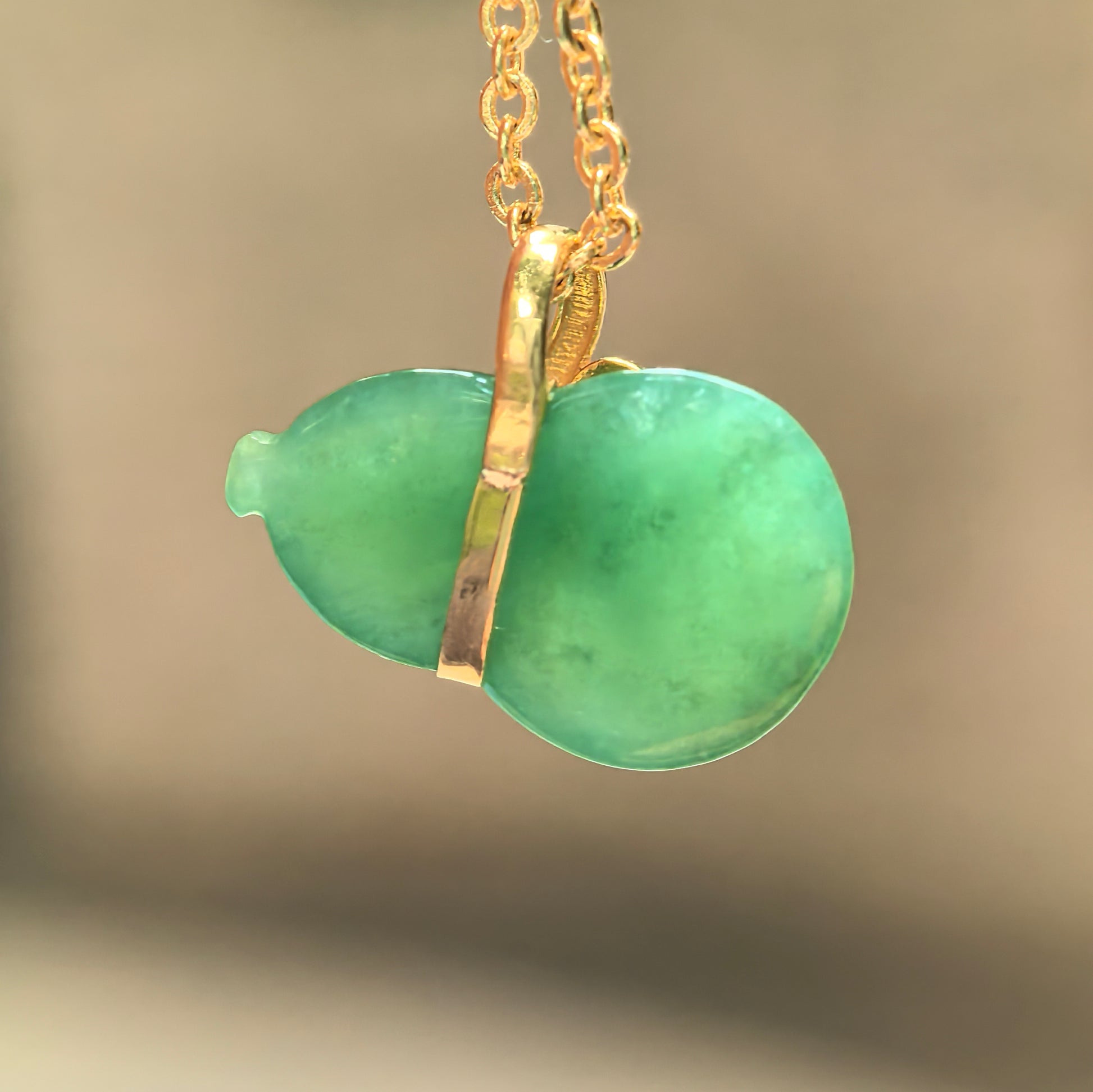 Back view of glutinous light green gourd jadeite pendant showing smooth jade texture and 18K gold setting.