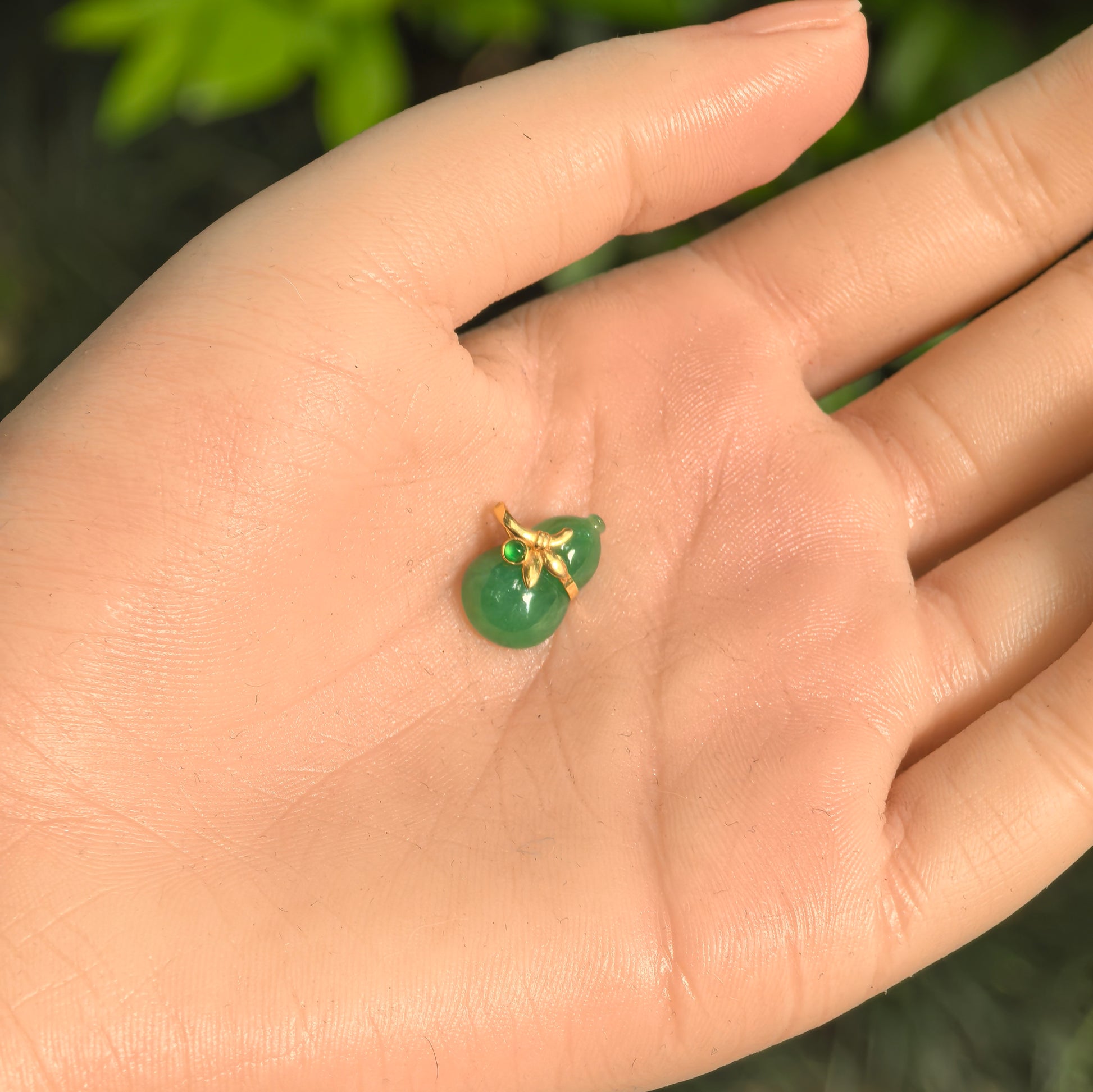 Natural Grade-A glutinous light green gourd jadeite pendant shown in hand for scale.