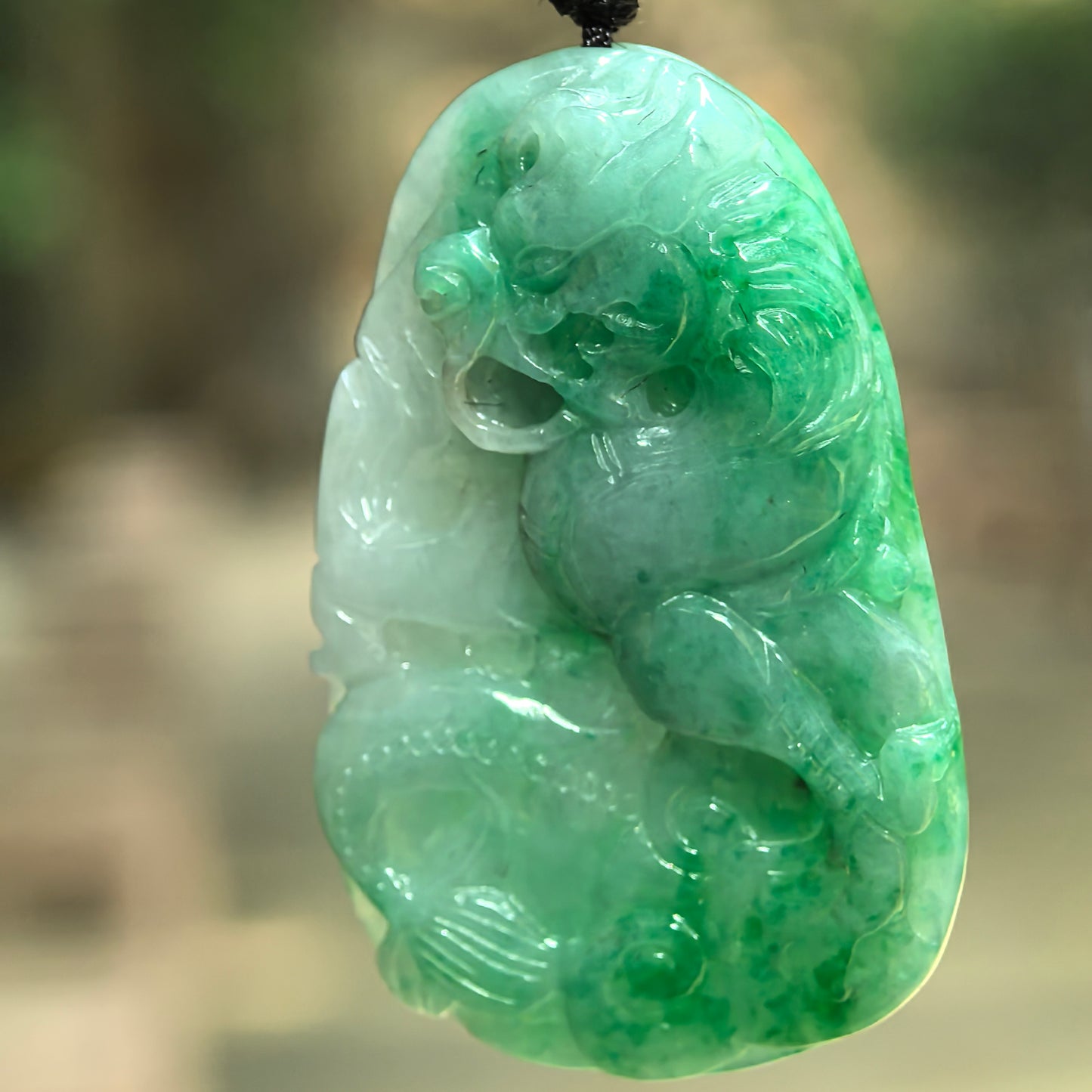 Natural Grade-A green jadeite dragon pendant hanging on cord with detailed dragon head, body, and carved decorative elements.