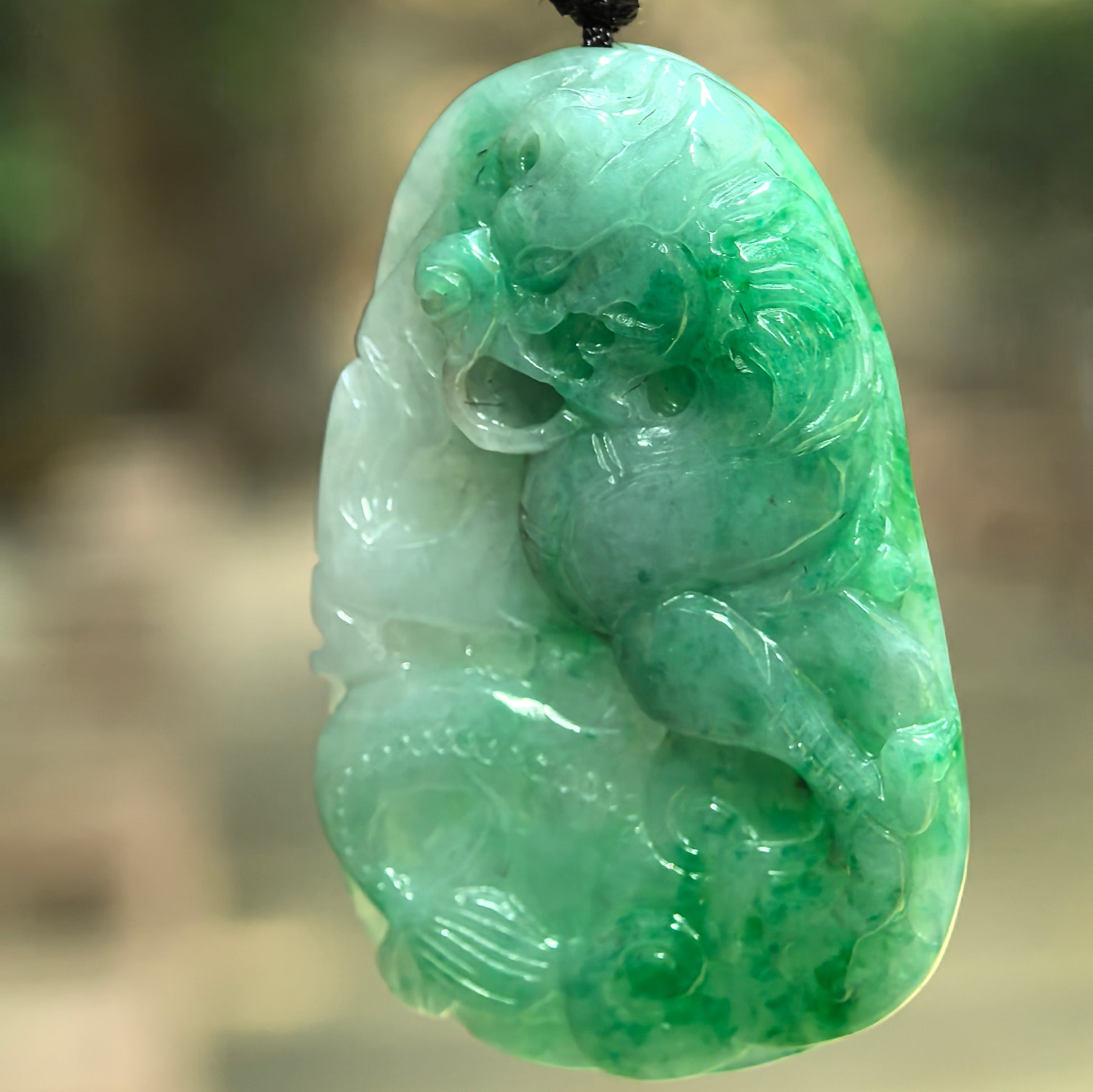 Natural Grade-A green jadeite dragon pendant hanging on cord with detailed dragon head, body, and carved decorative elements.
