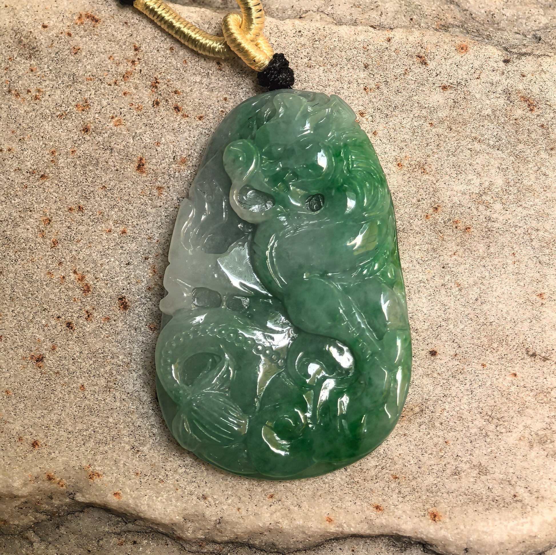 Close-up of green jadeite dragon plaque pendant showing glossy polish, light green areas, and sculptural dragon carving.