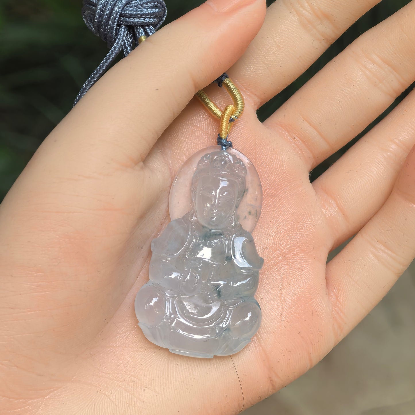 Natural Grade-A icy glutinous light green white Guanyin jadeite pendant displayed on hand.
