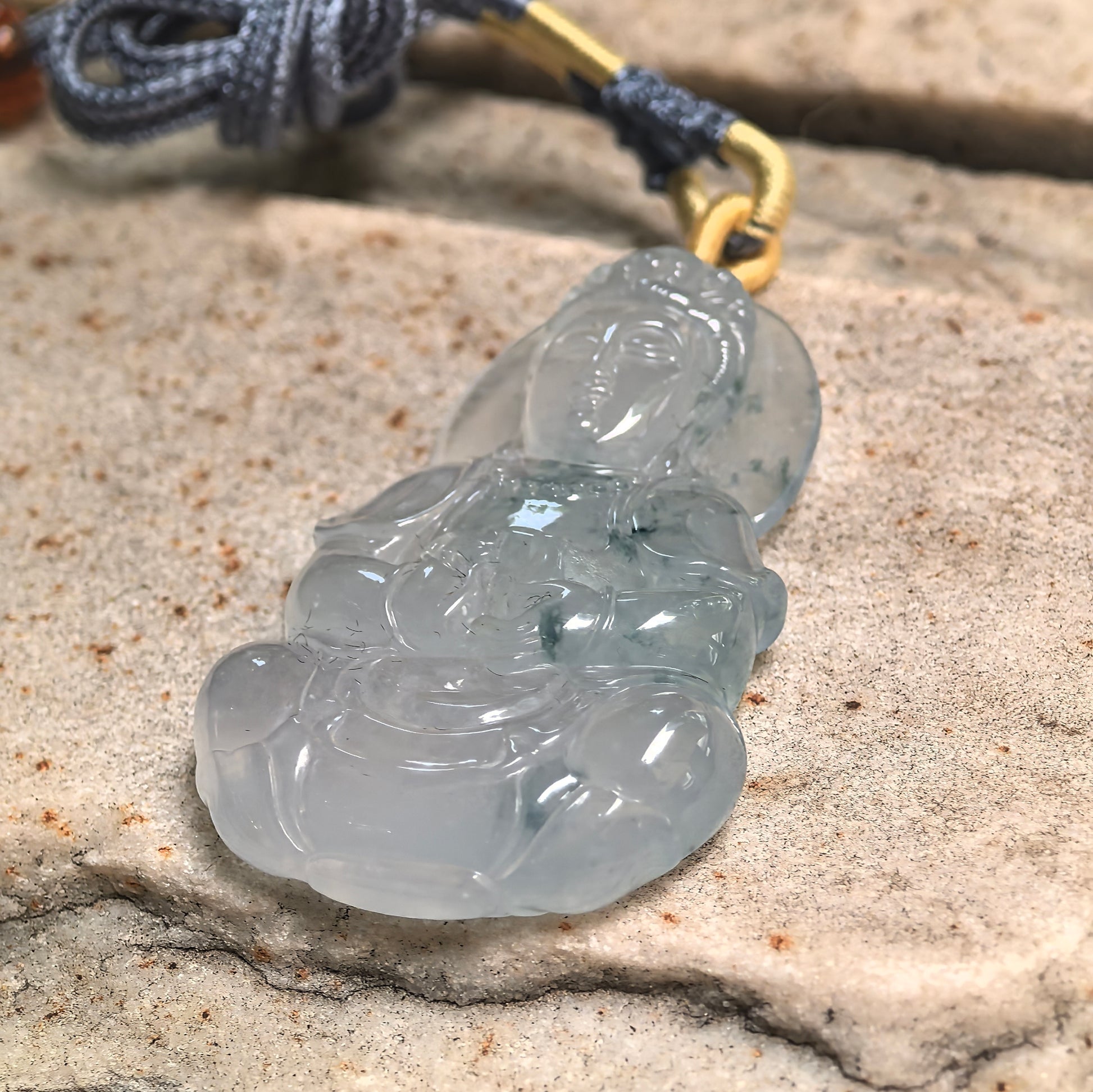 Side view of carved Guanyin jadeite pendant showing three-dimensional lotus-seat design.

