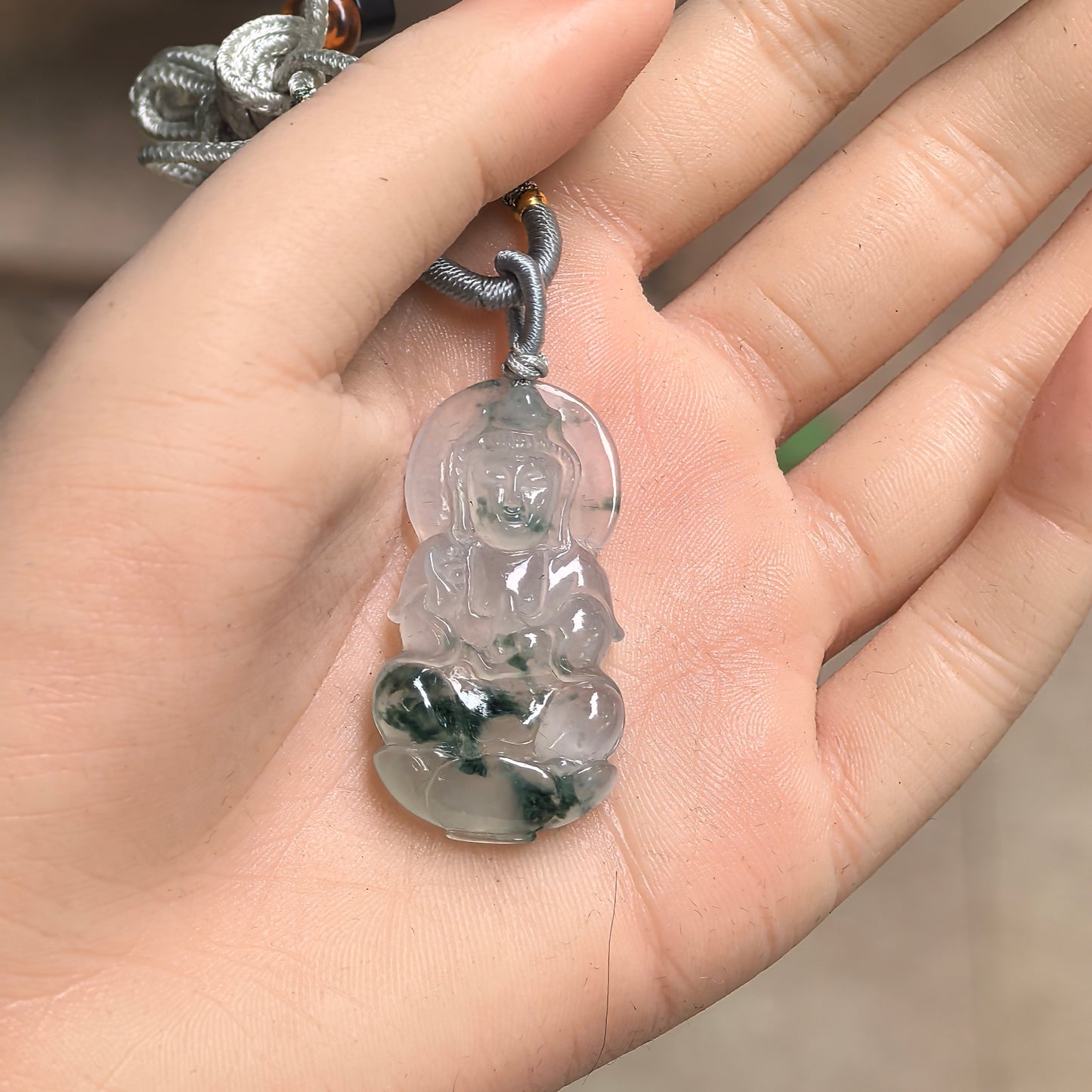 Light green floating green flower jadeite Guanyin pendant displayed on hand.
