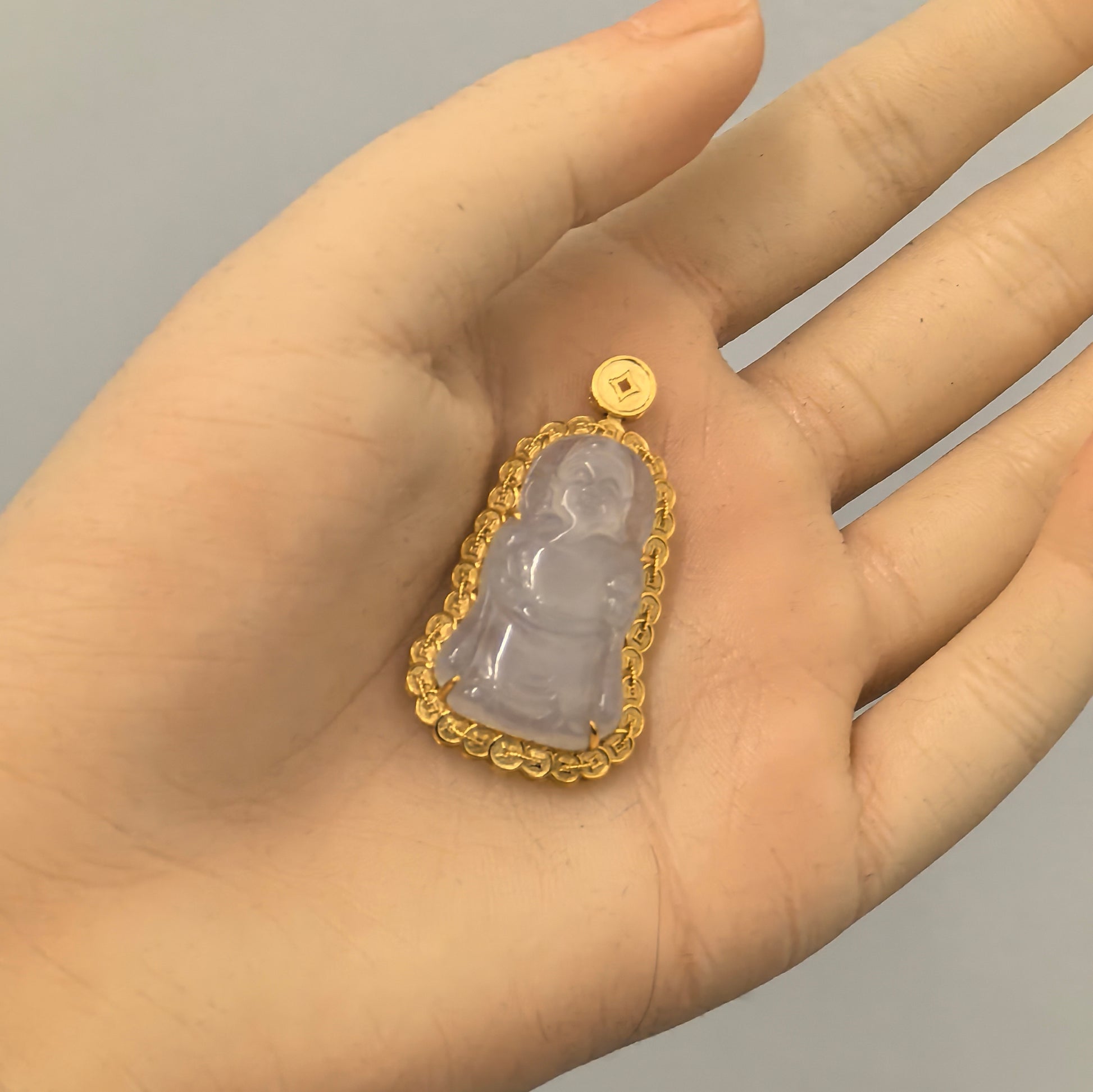 Natural Grade-A icy glutinous white jadeite God of Wealth pendant with 18K gold setting shown in hand.