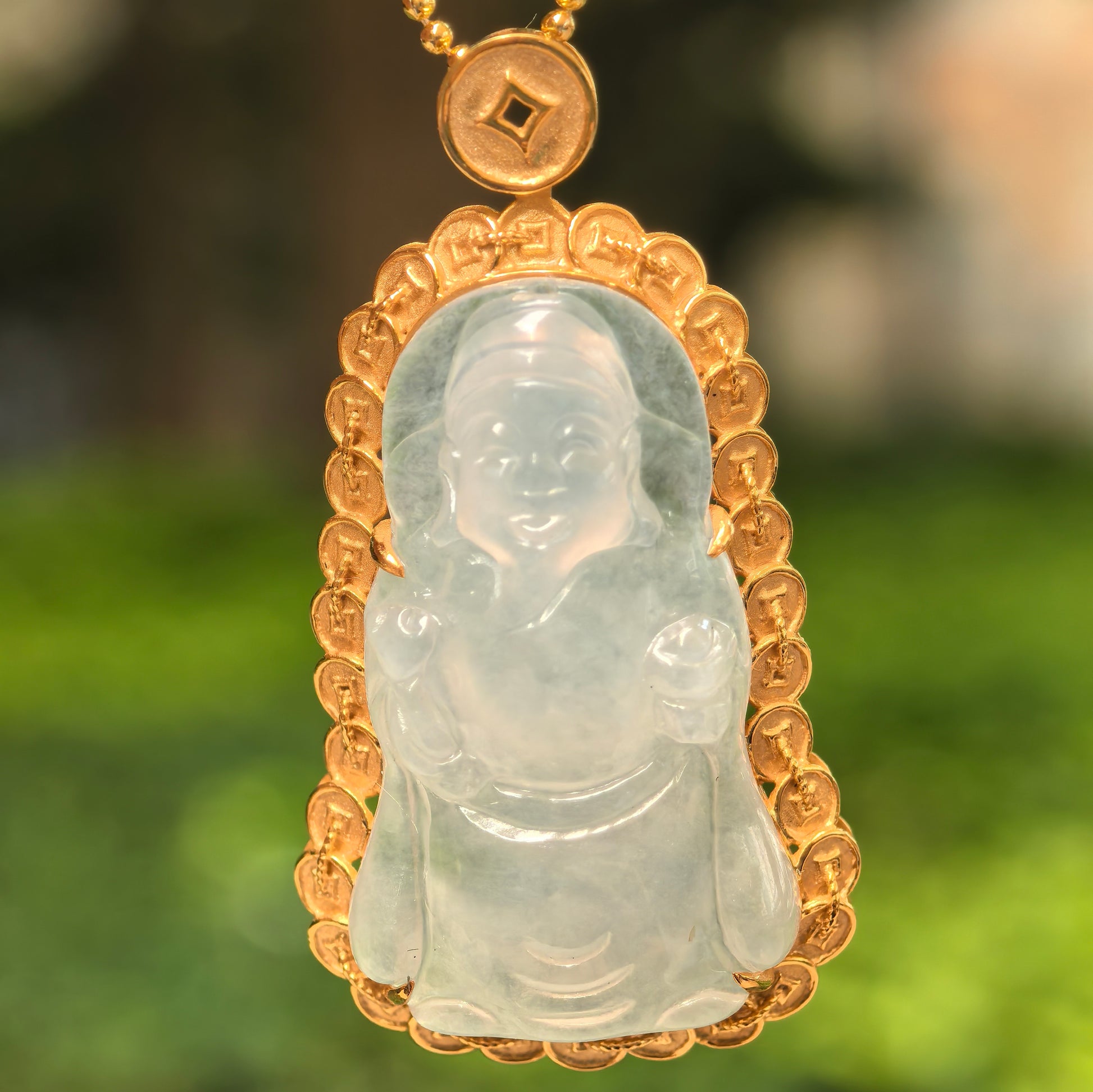 Close-up of white jadeite God of Wealth carving with detailed 18K gold coin-inspired frame.