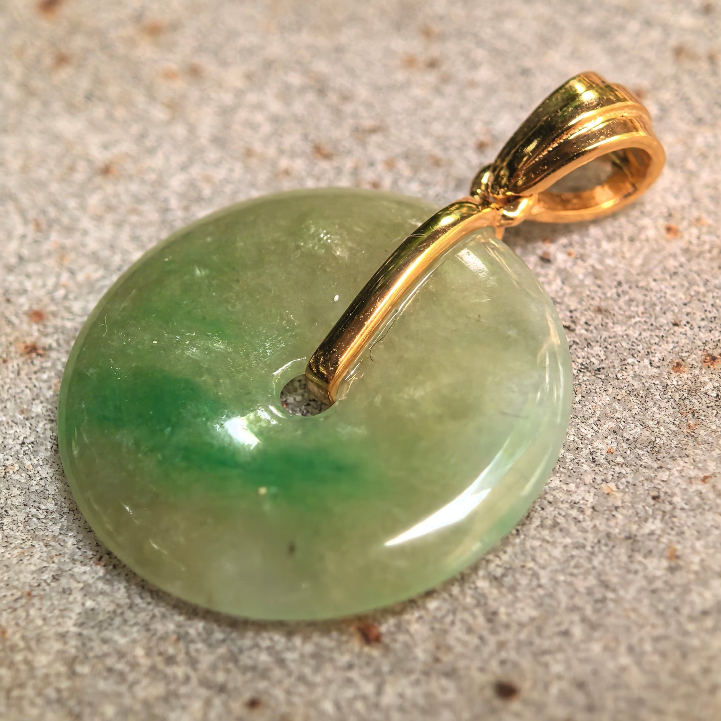 Close-up side view of yellow-green jadeite Peace Pendant showing smooth polish and natural texture.
