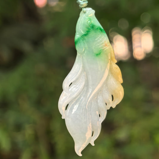 Natural Grade-A glutinous yellow-green jadeite fish pendant hanging in natural light.