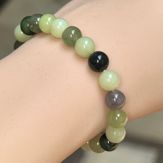 Natural multicolor Hetian jade bead bracelet worn on the wrist with yellow-green, dark green, white, gray, and brown beads.
