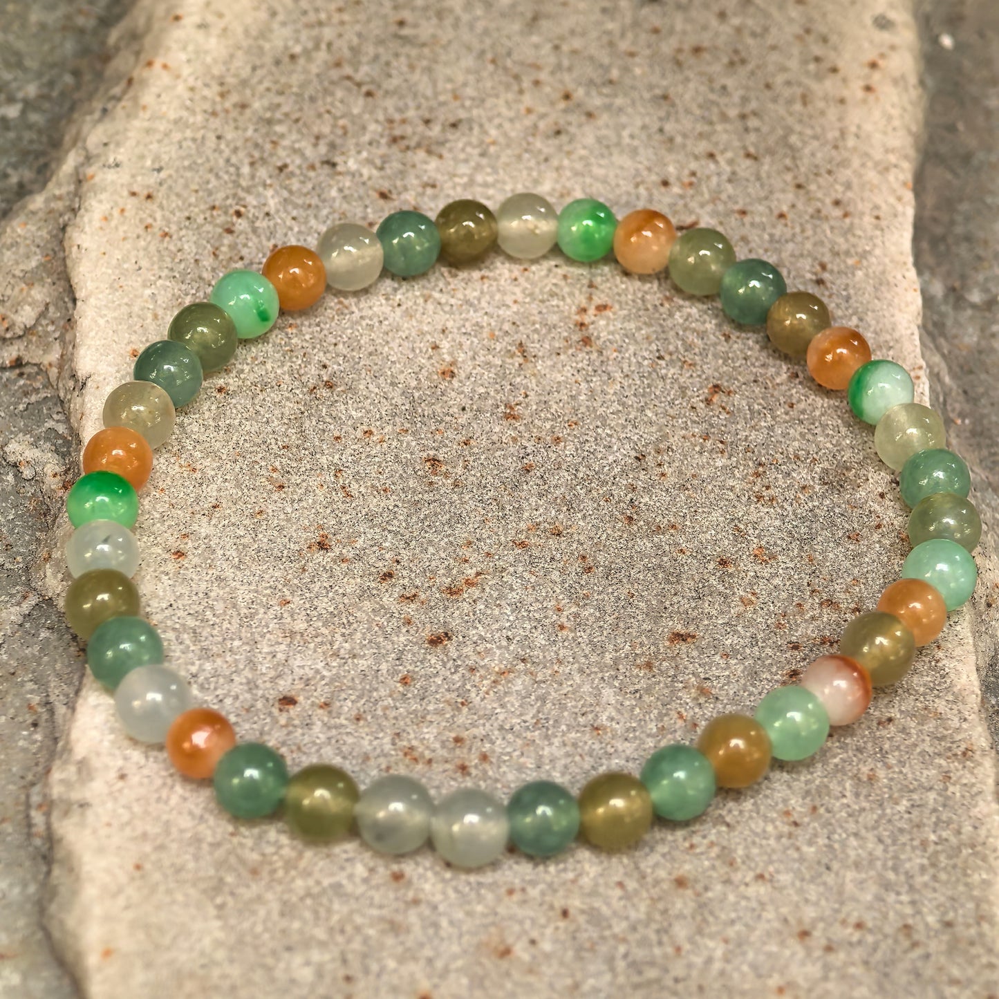 Angled view of polished glutinous icy multicolor jadeite round-bead bracelet.
