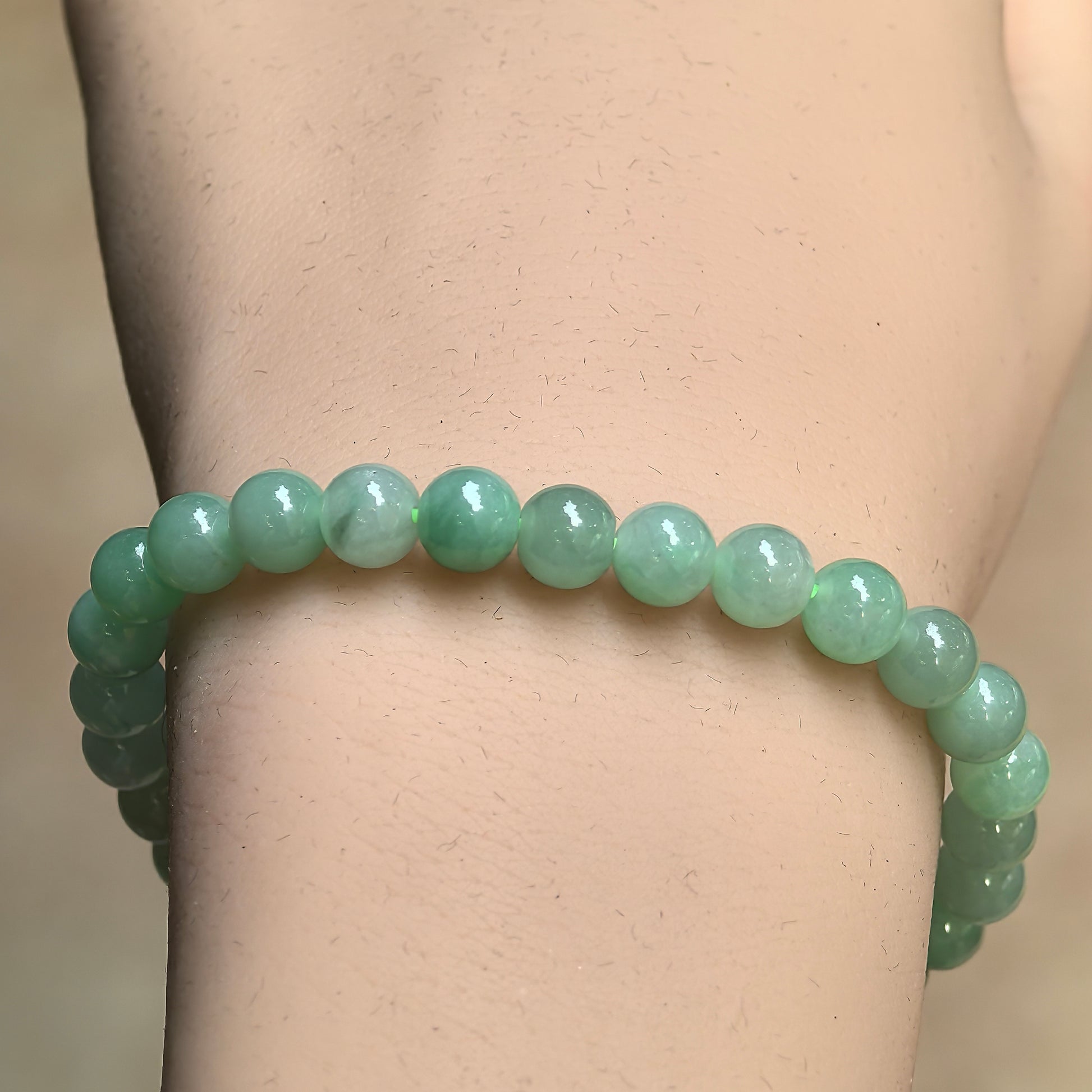 Close-up of light green jadeite bead bracelet showing natural green variations and polished surface.