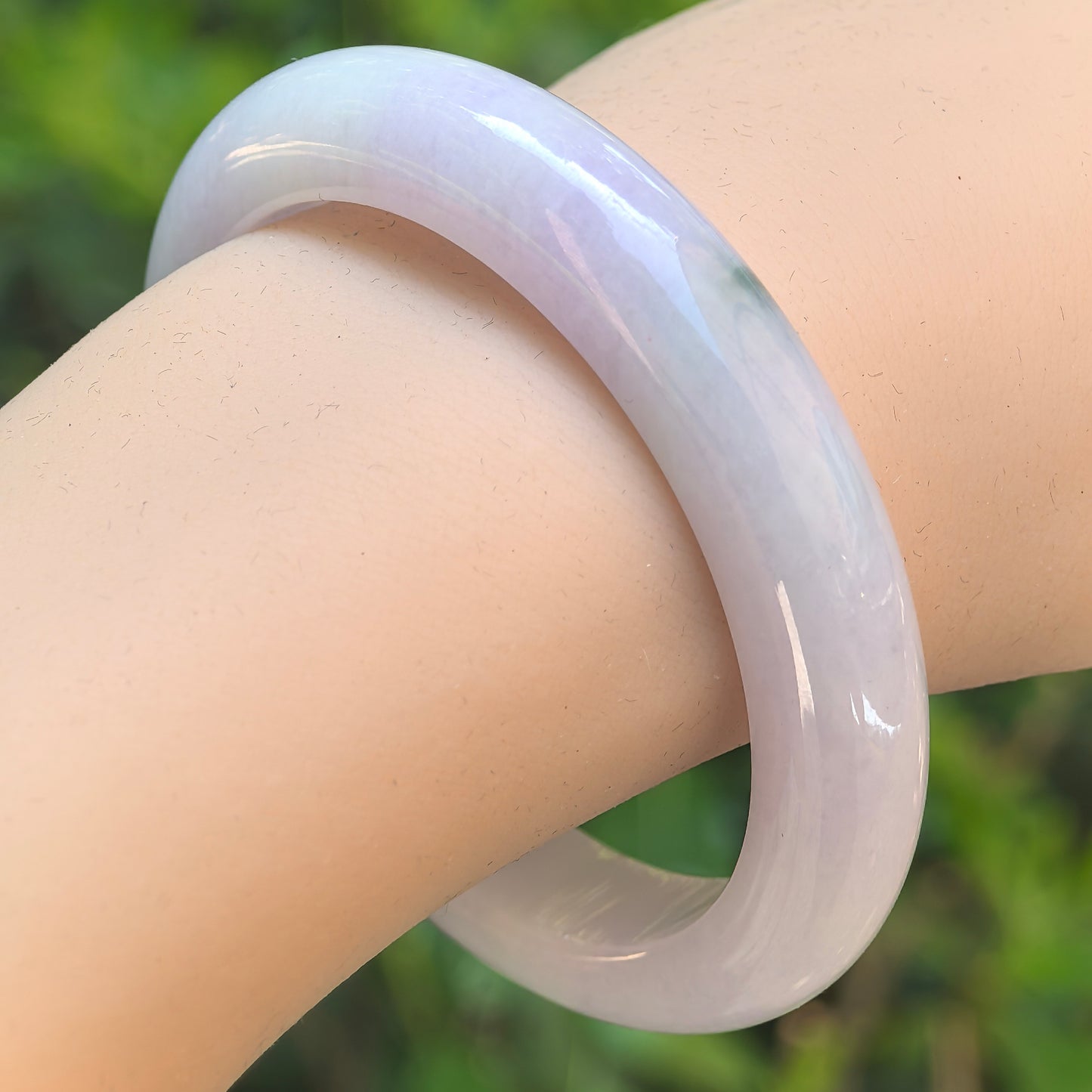 Natural Grade-A glutinous pale lavender jadeite bangle worn on wrist with smooth polished surface.