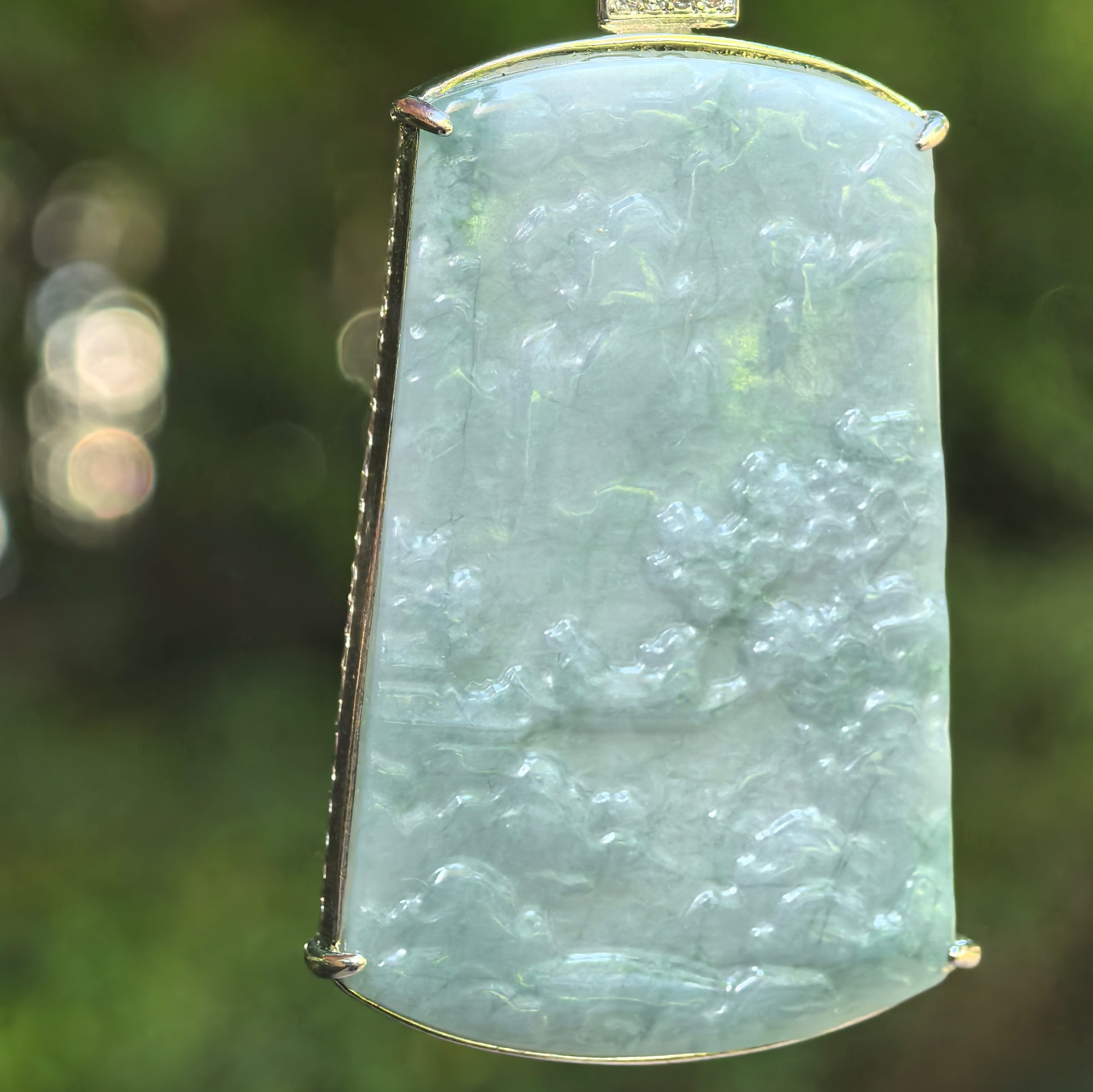 Natural Grade-A glutinous teal blue Guatemalan jadeite landscape pendant shown in close-up with carved scenery.