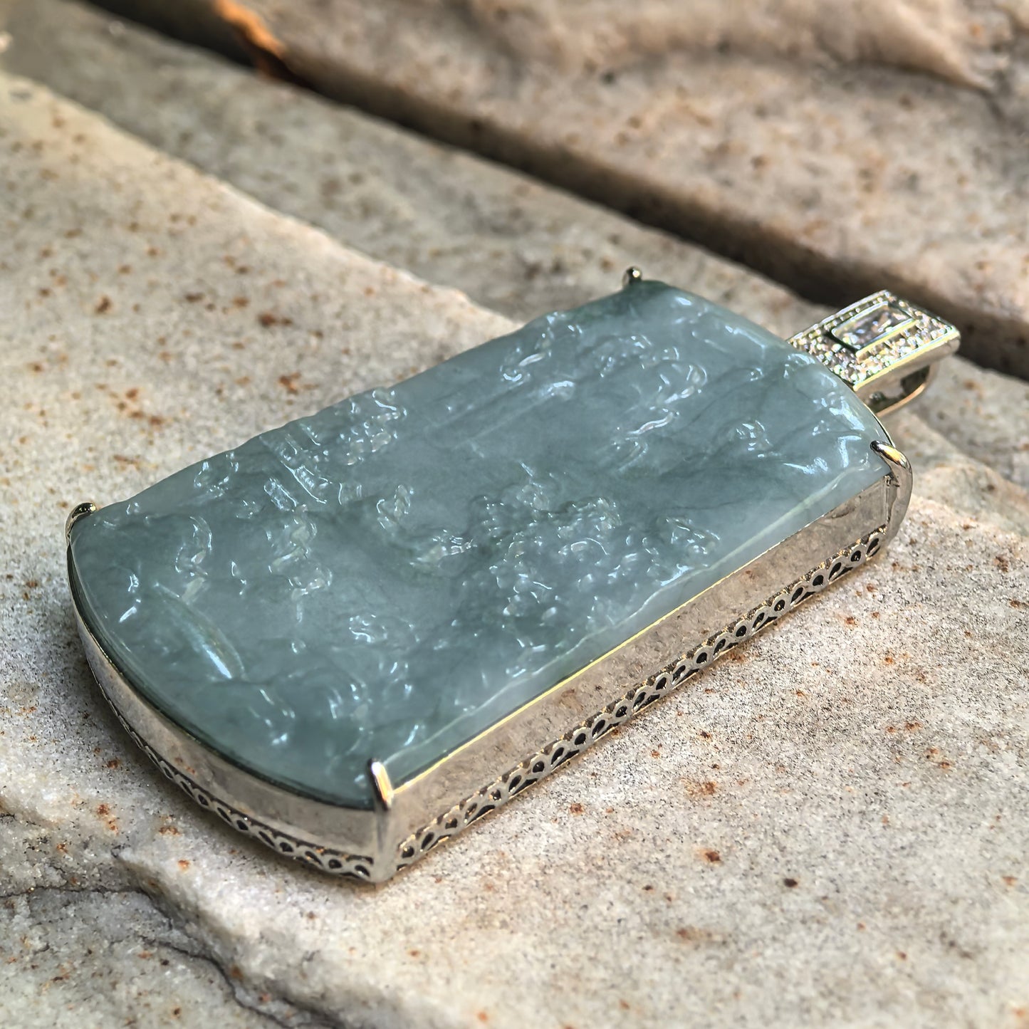 Side view of glutinous teal blue jadeite pendant showing thickness, polish, and non-precious metal frame.