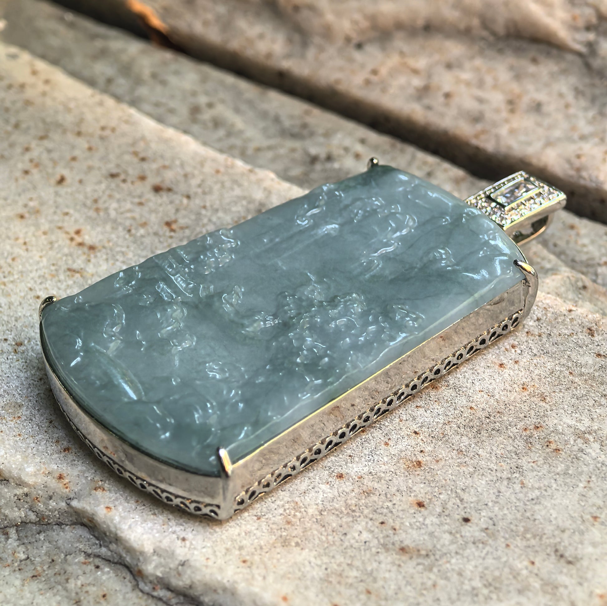 Side view of glutinous teal blue jadeite pendant showing thickness, polish, and non-precious metal frame.
