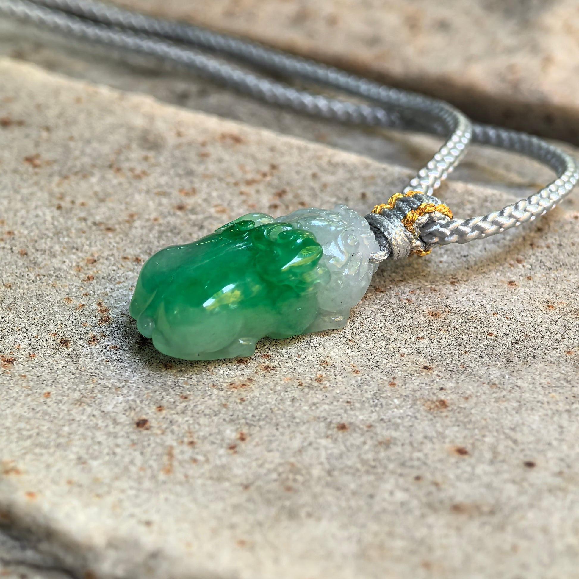 Side view of half-green Pixiu jadeite pendant showing three-dimensional carving and rounded thickness.