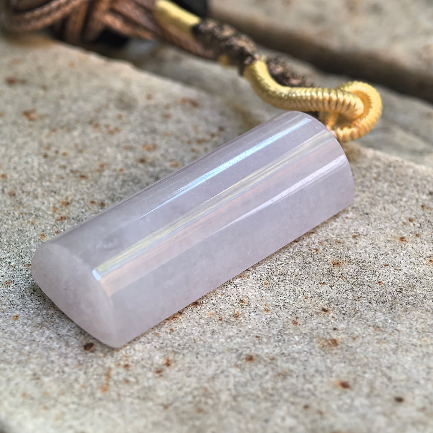 Side view of icy glutinous lavender jadeite pillar pendant with polished curved profile.

