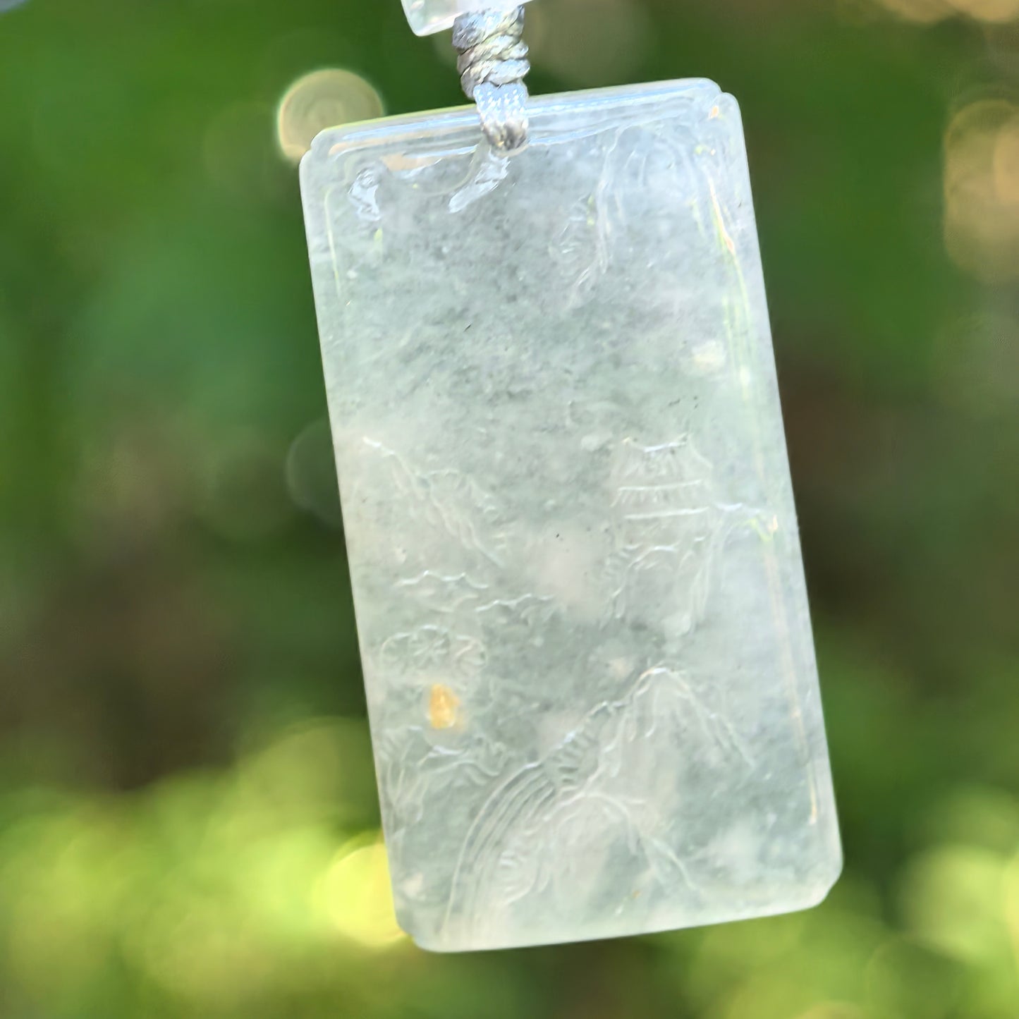 Natural Grade-A icy glutinous white landscape jadeite pendant hanging on cord with soft translucent texture.