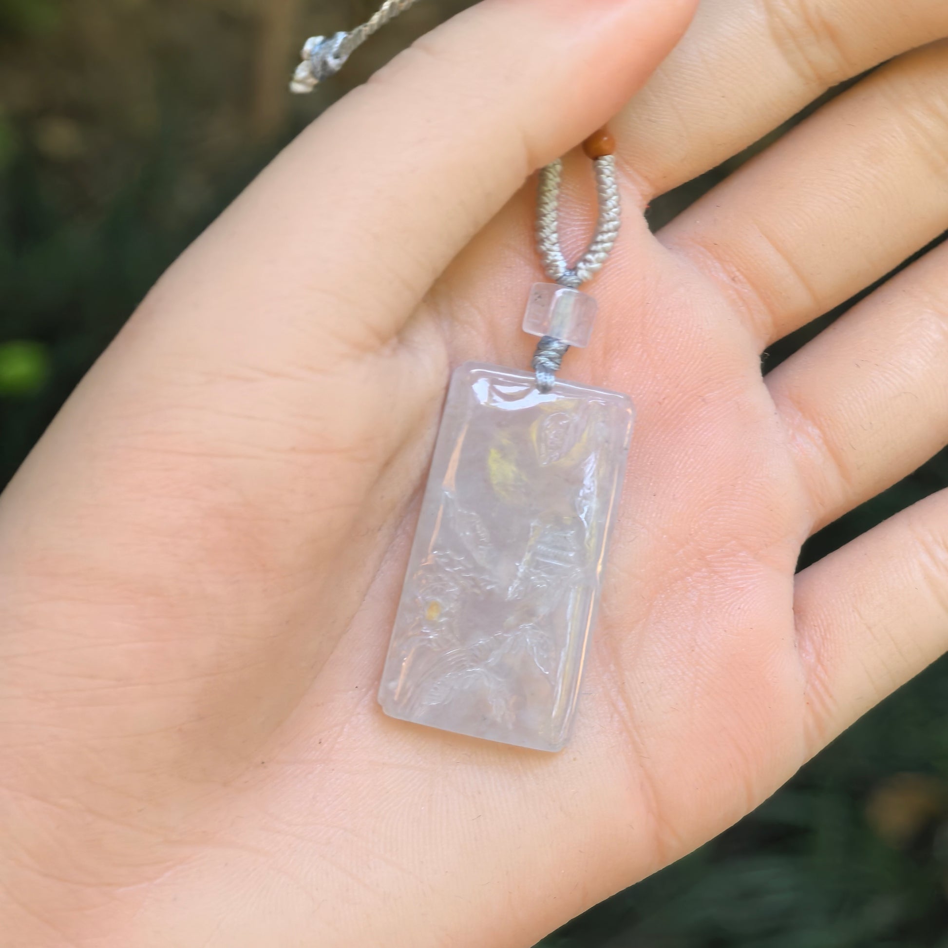 Close-up of white landscape jadeite pendant showing carved mountain and pavilion details.
